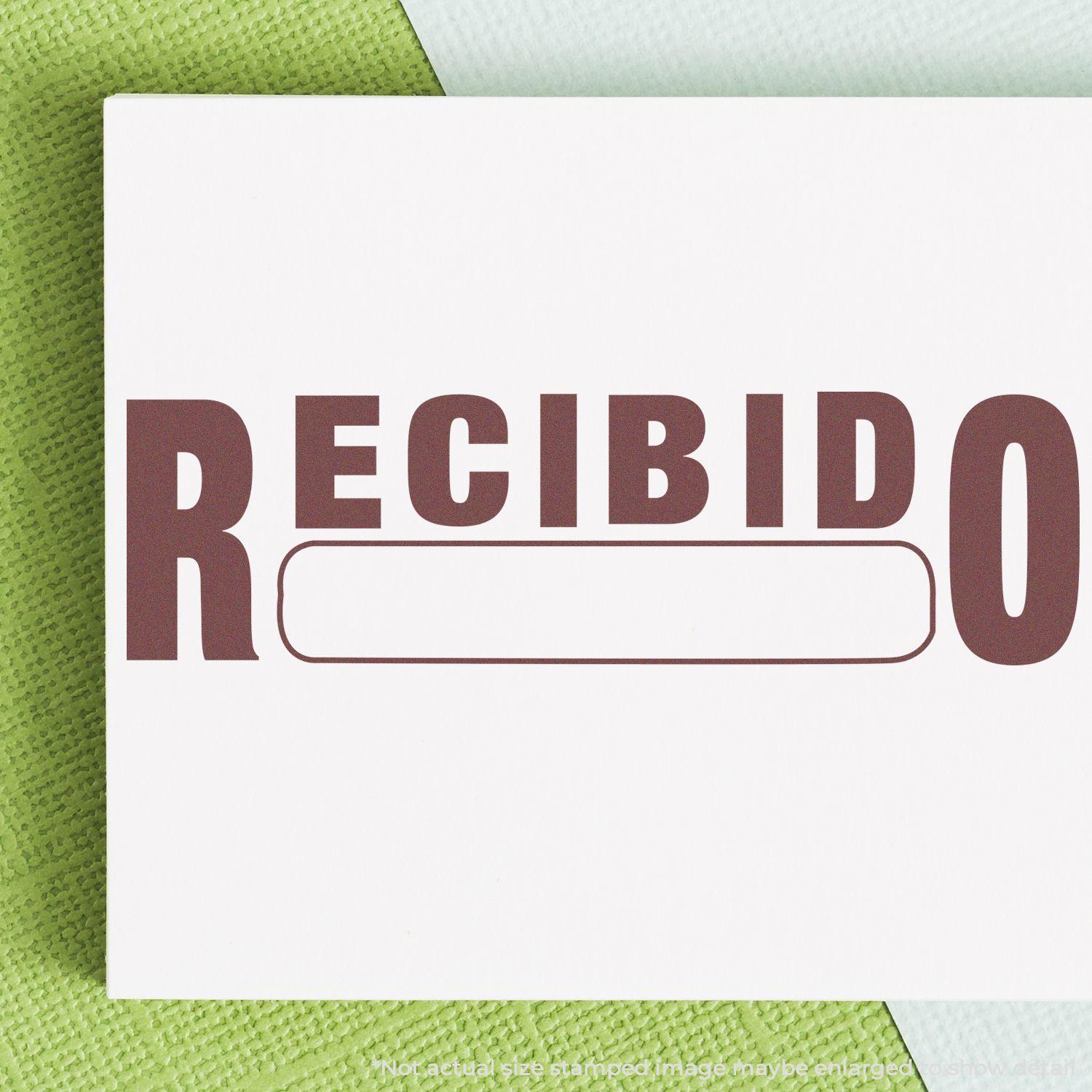 Slim Pre-Inked Recibido Stamp impression on white paper with green textured background.