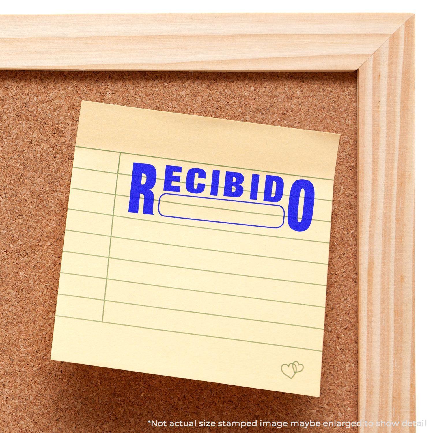 Yellow sticky note on a corkboard stamped with "Recibido" in blue ink using the Recibido Rubber Stamp.