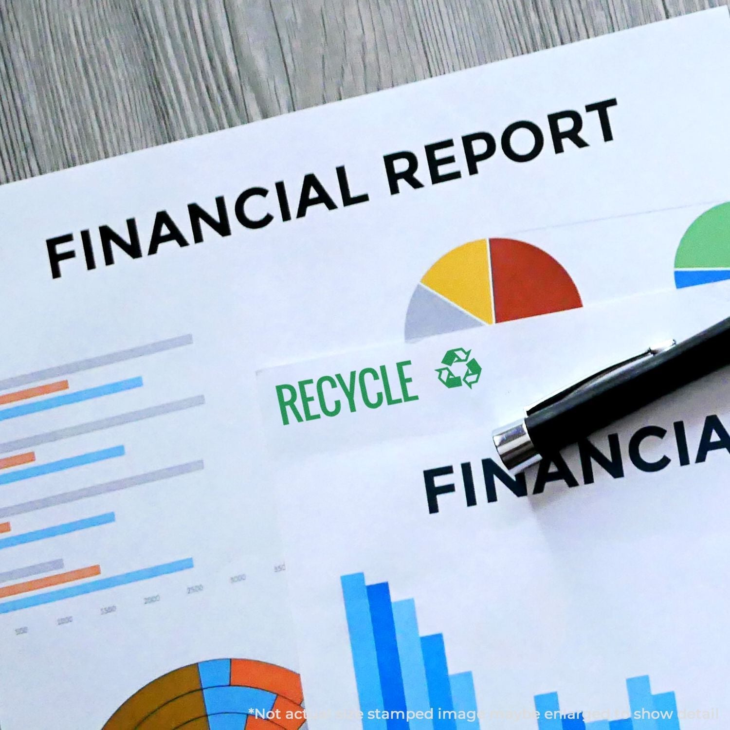 Financial reports stamped with the Self Inking Recycle with Logo Stamp, featuring charts and a pen on a wooden surface.