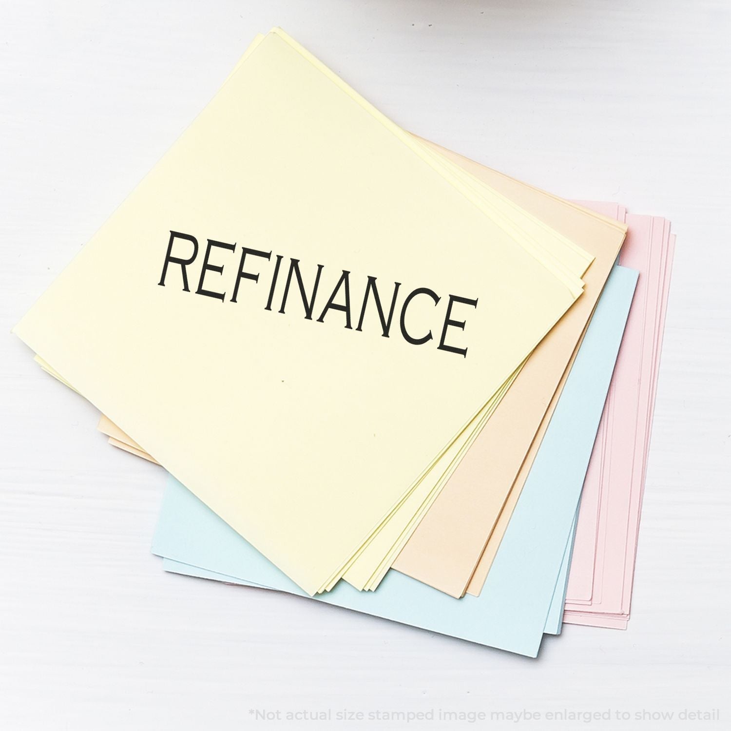 Stack of pastel-colored papers stamped with REFINANCE using the Self Inking Refinance Stamp, placed on a white surface.