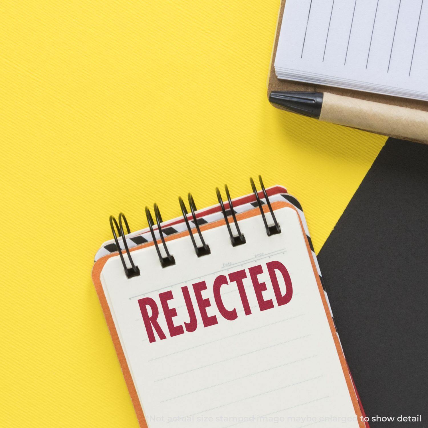 Notebook with 'REJECTED' stamped in red using a Slim Pre-Inked Rejected Stamp, placed on a yellow and black background.