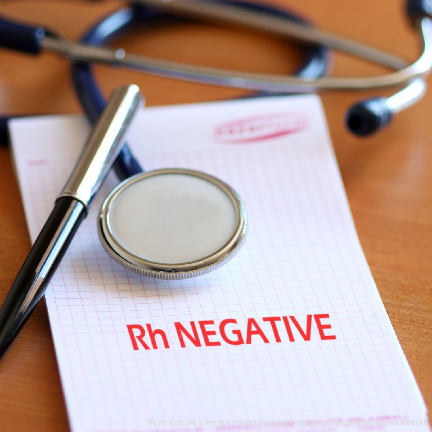 Self Inking Rh Negative Stamp on a notepad with a stethoscope and pen on a wooden desk.