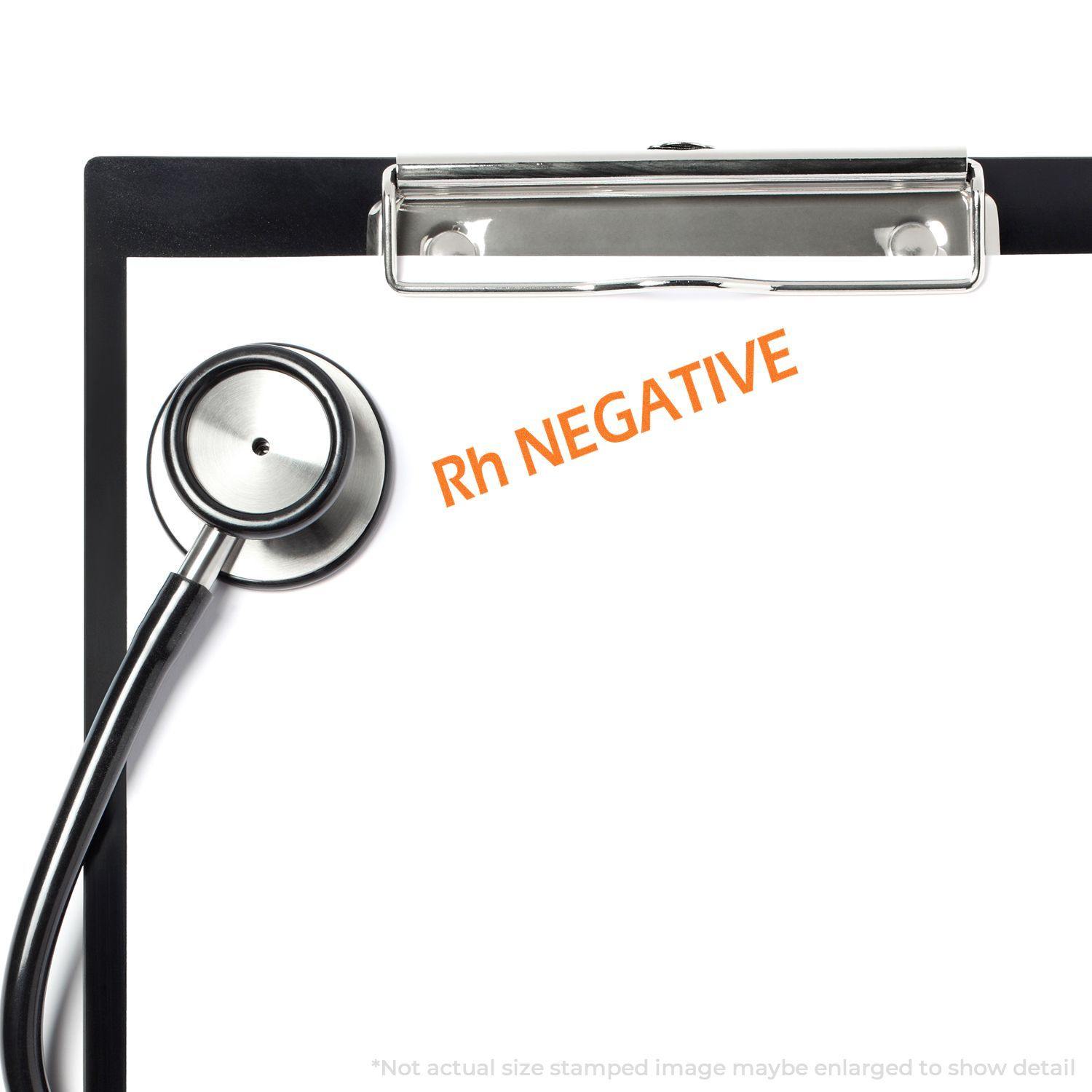 Clipboard with stethoscope and Rh Negative rubber stamp in orange ink on a blank white paper.