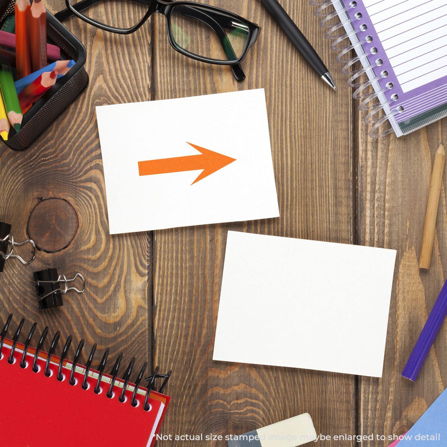 Round Arrow Rubber Stamp on a wooden desk with stationery items including notebooks, glasses, pens, and paper clips.