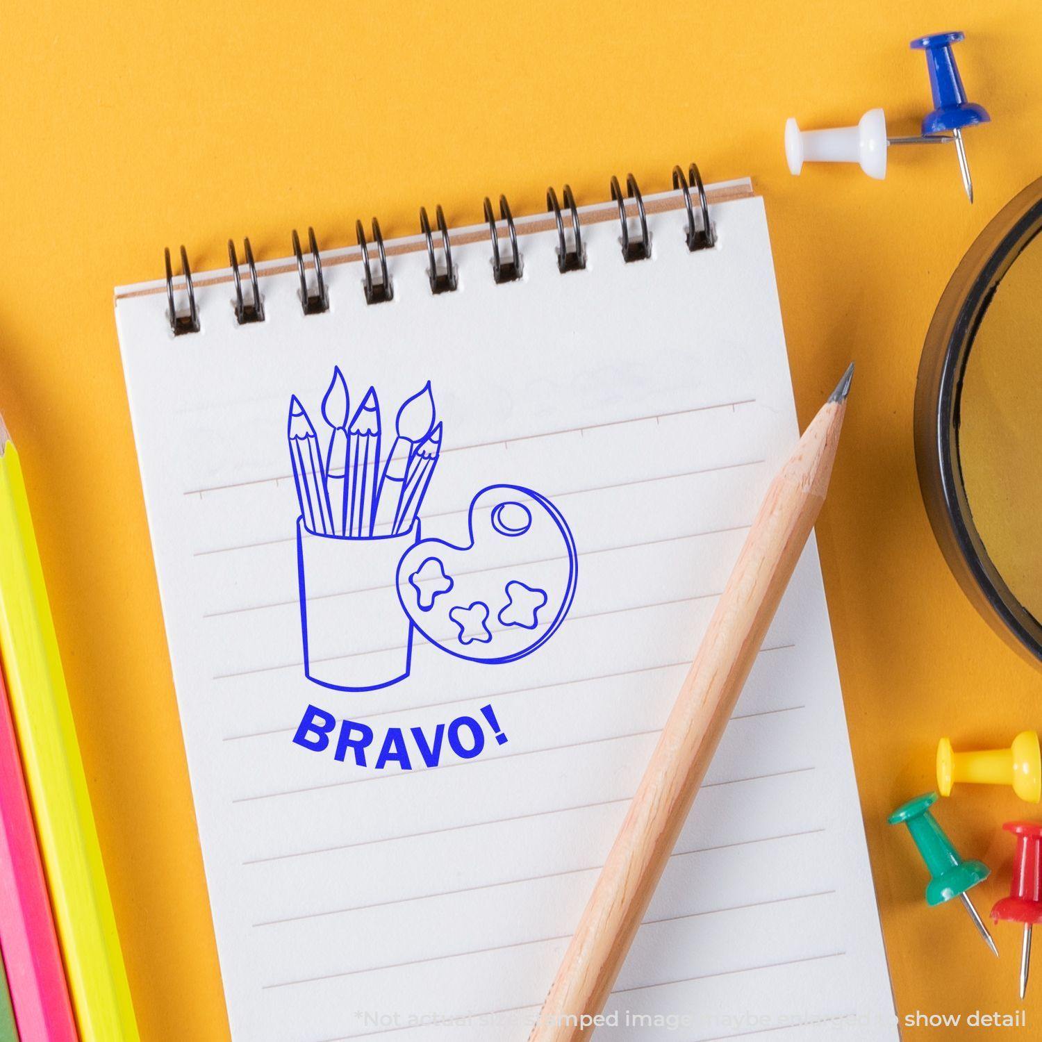 Round Bravo rubber stamp with art supplies design on a notepad, surrounded by colored pencils, push pins, and a pencil.