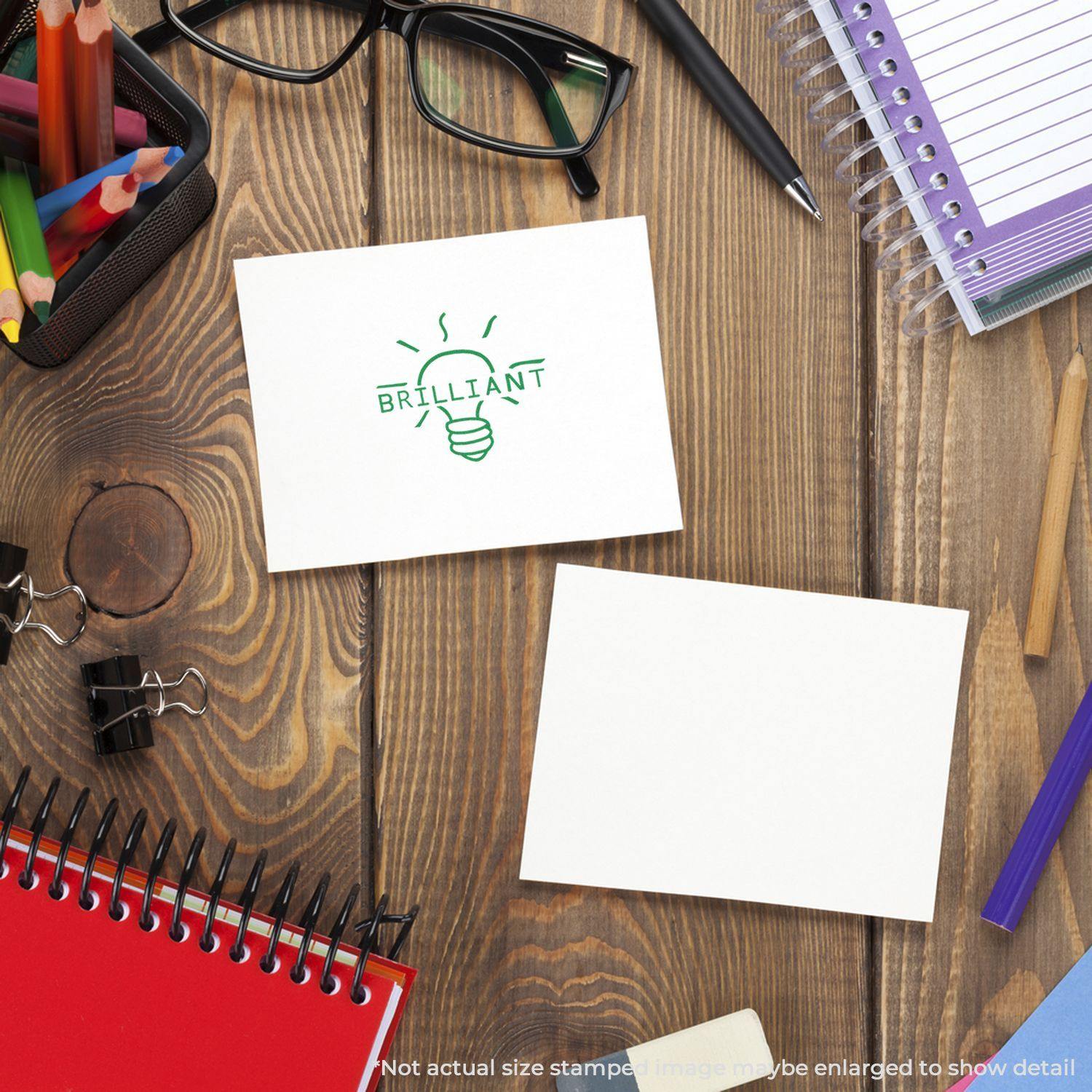 Round Brilliant Rubber Stamp on a white card, surrounded by office supplies including glasses, notebooks, and pens on a wooden desk.