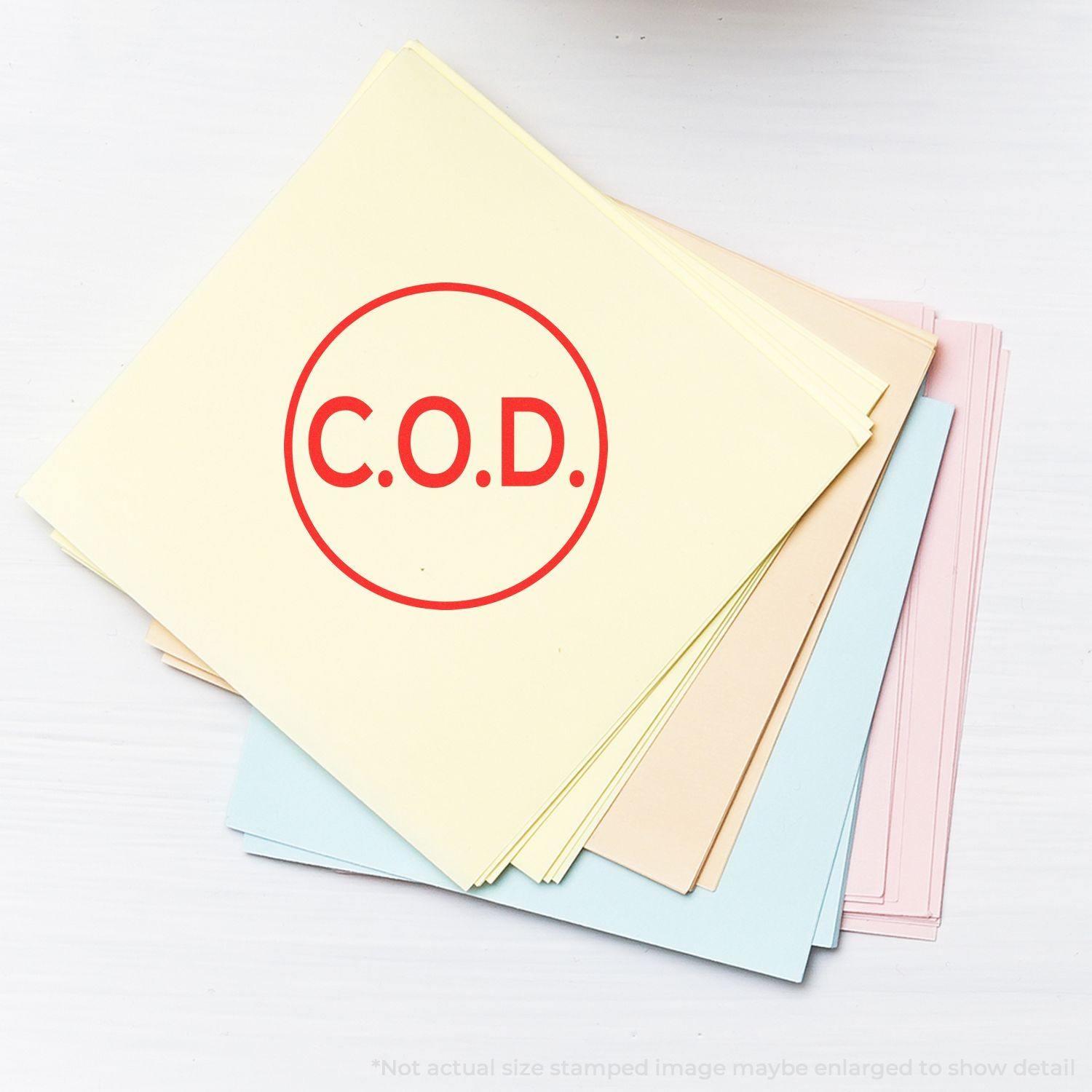 Round COD Rubber Stamp in red ink on a stack of pastel-colored papers. The stamp reads "C.O.D." inside a circle.