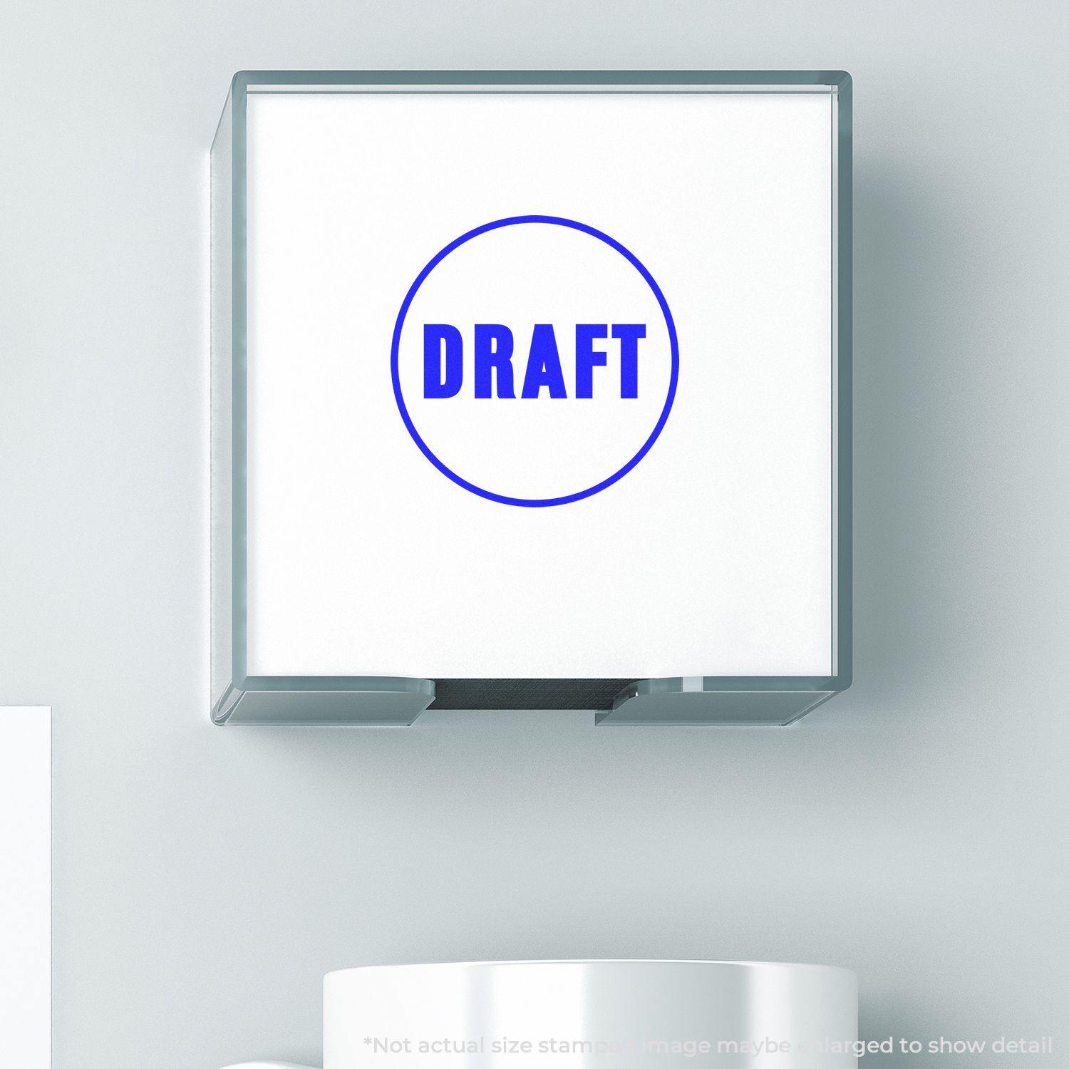 Round Draft Rubber Stamp in blue ink on a white surface, encased in a clear plastic holder, with a mug partially visible below.