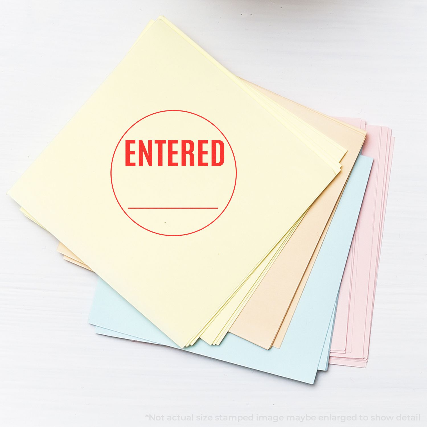 A stack of pastel-colored papers stamped with ENTERED using the Self Inking Round Entered Stamp, showing a clear red imprint.