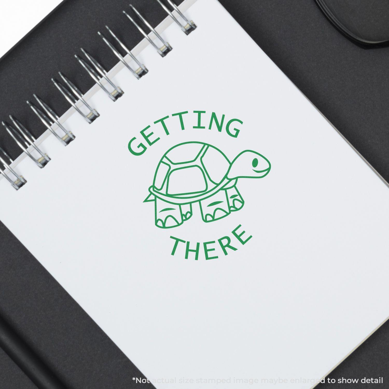 Round Getting There Rubber Stamp with a green turtle design on a white notebook page, symbolizing slow but steady progress.