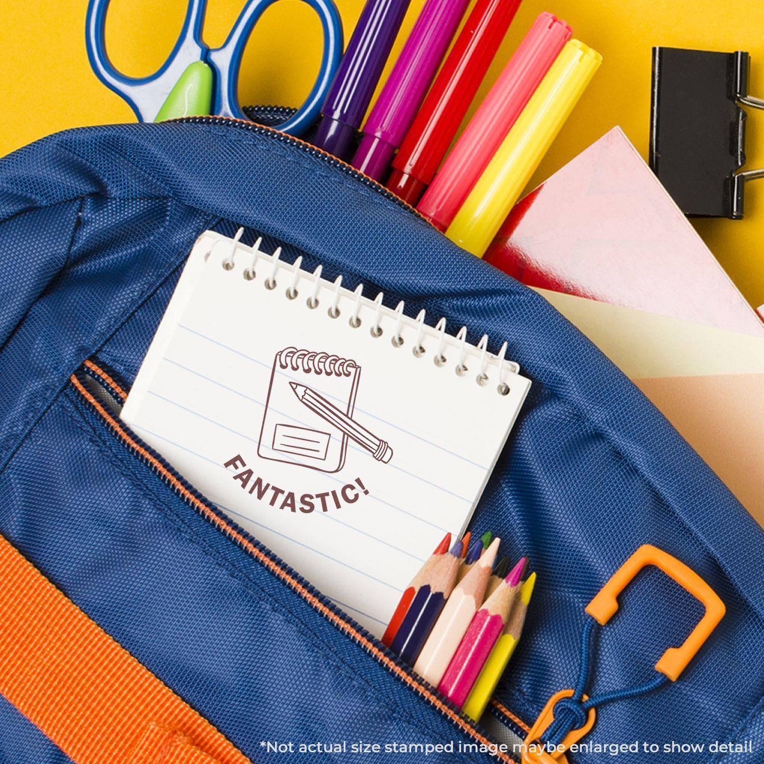 A blue backpack with colored pencils, scissors, and a notebook stamped with a Round Fantastic Rubber Stamp design.