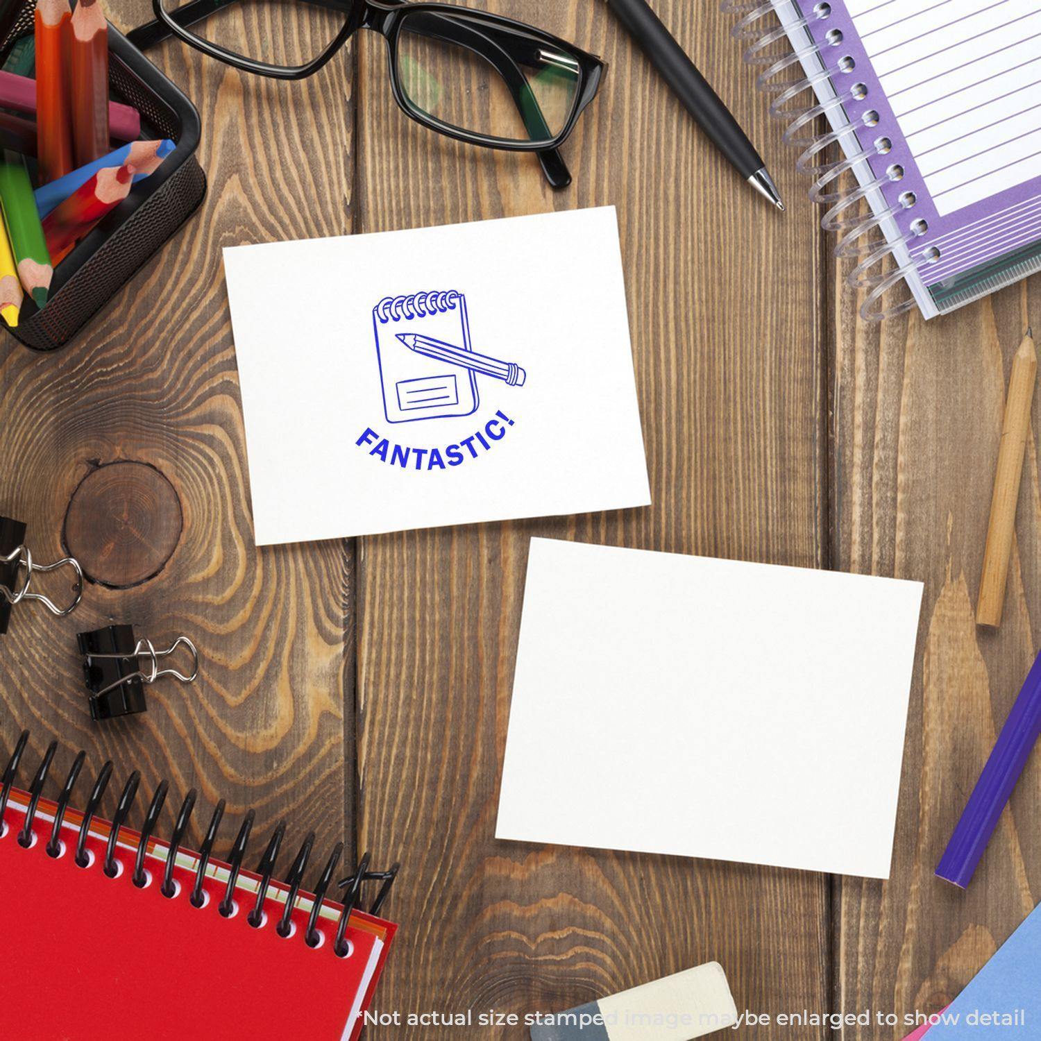 A desk with stationery items and a card stamped with a Round Fantastic Rubber Stamp featuring a pencil and the word Fantastic!