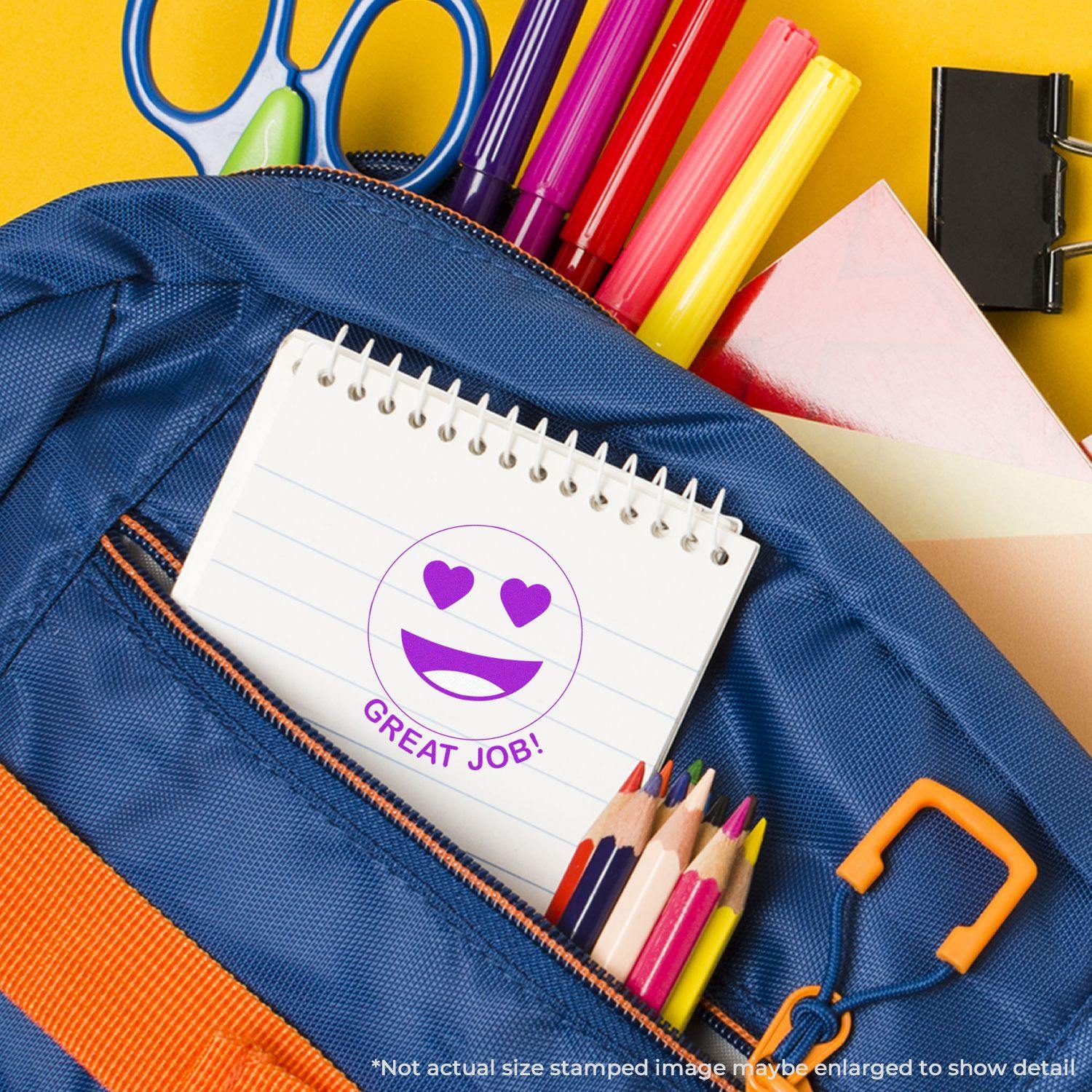 Round Great Job Smiley Rubber Stamp on a notebook inside a blue backpack with colored pencils, markers, and scissors nearby.