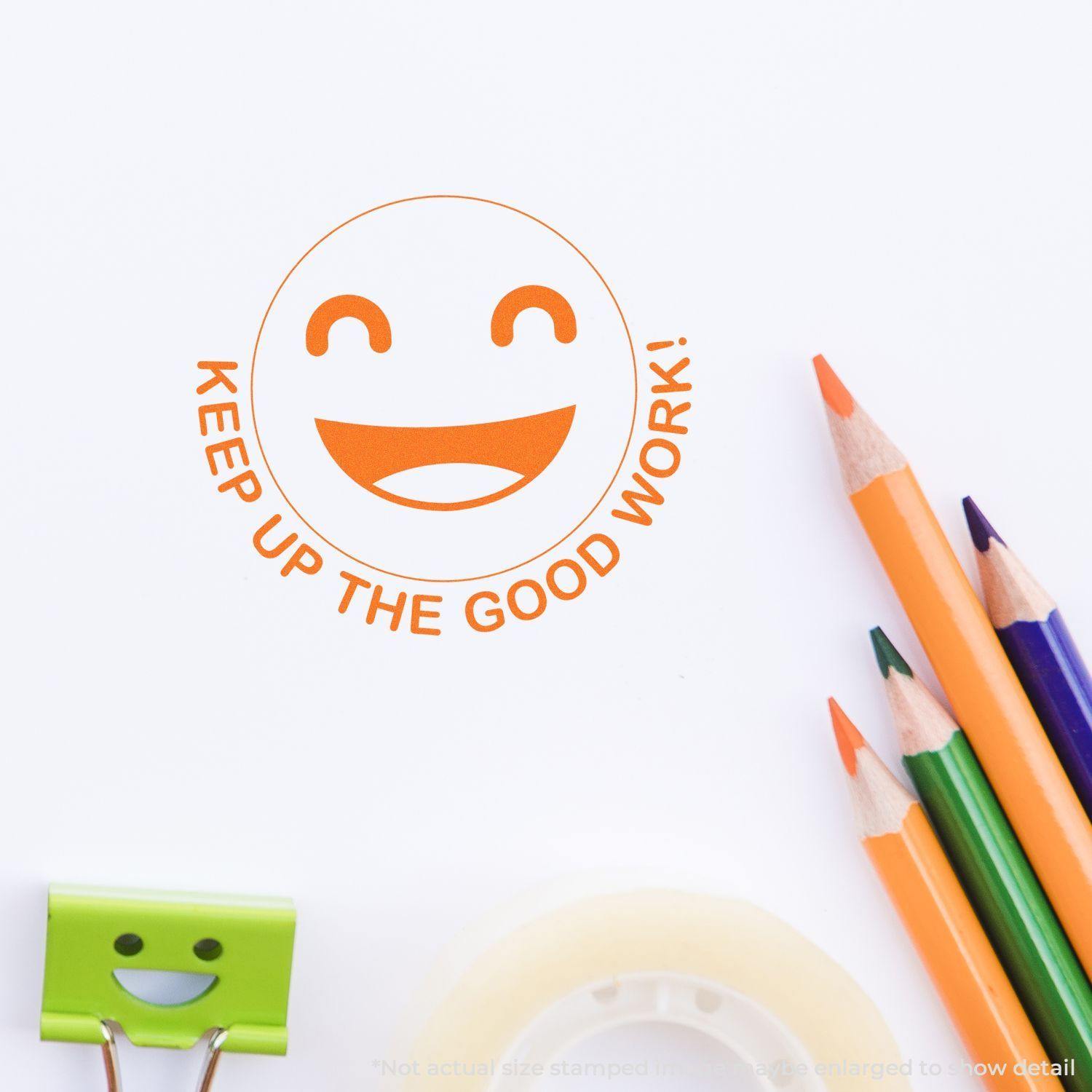 Round Keep up the Good Work Smiley Rubber Stamp in orange ink on white paper, surrounded by colorful pencils and a smiley clip.