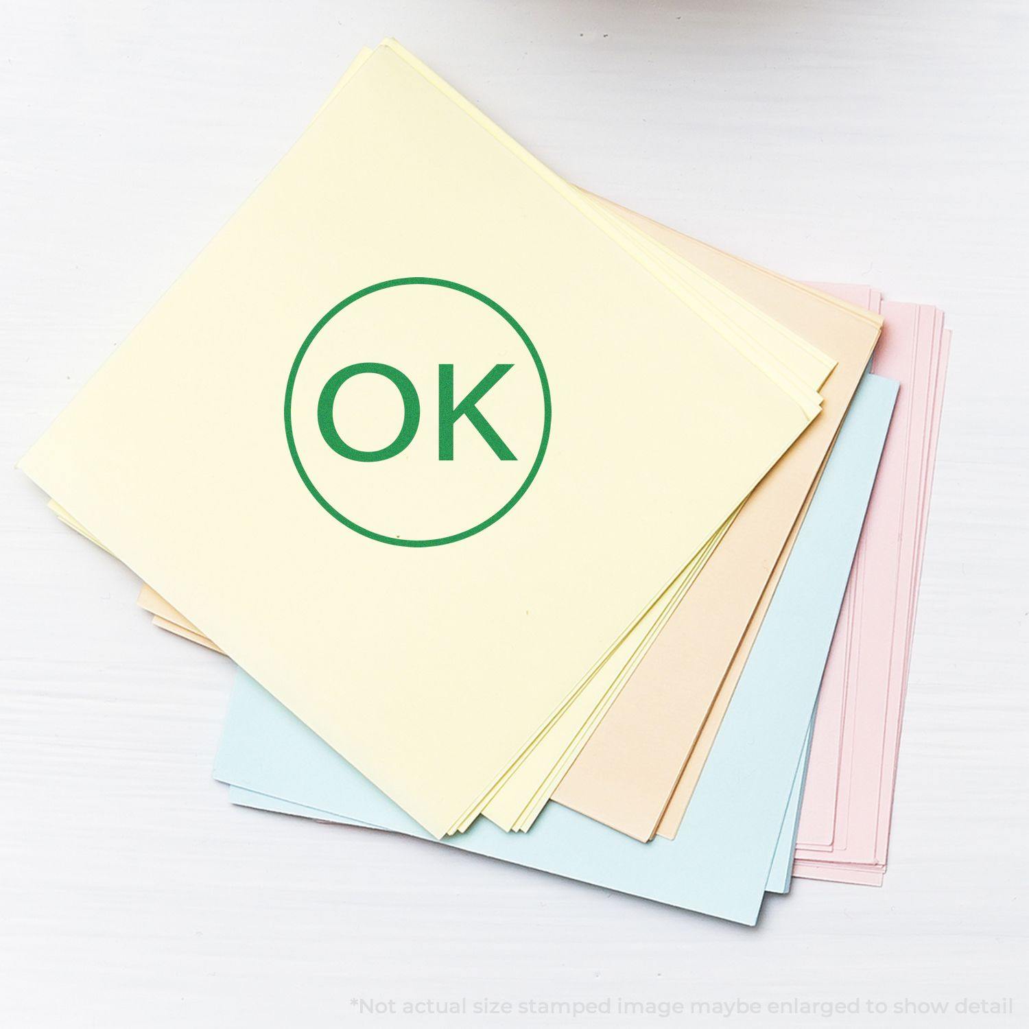 A stack of pastel-colored papers with a green Round OK Rubber Stamp mark on the top sheet.