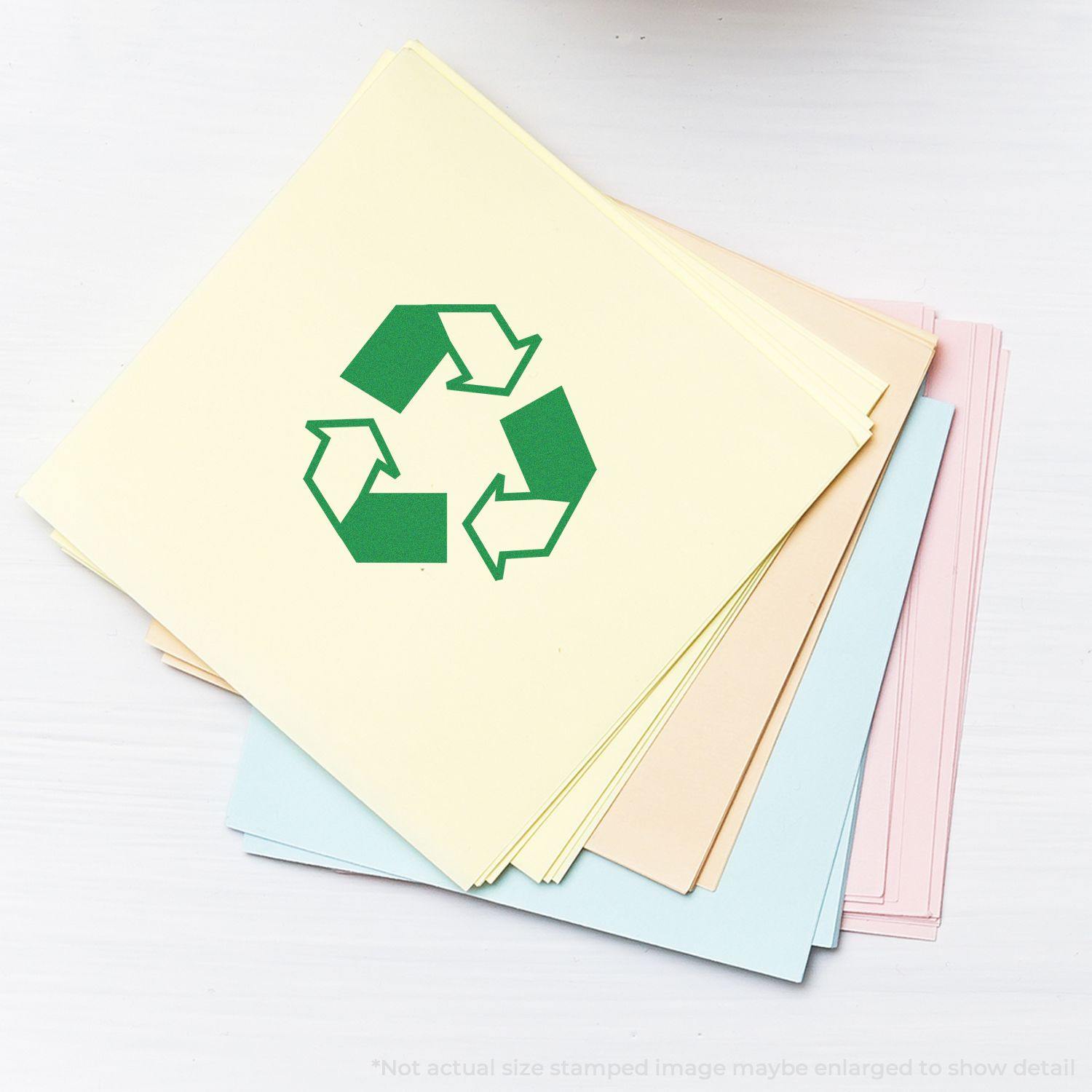 Round Recycle Rubber Stamp on a stack of pastel-colored papers, featuring a green recycling symbol in the center.