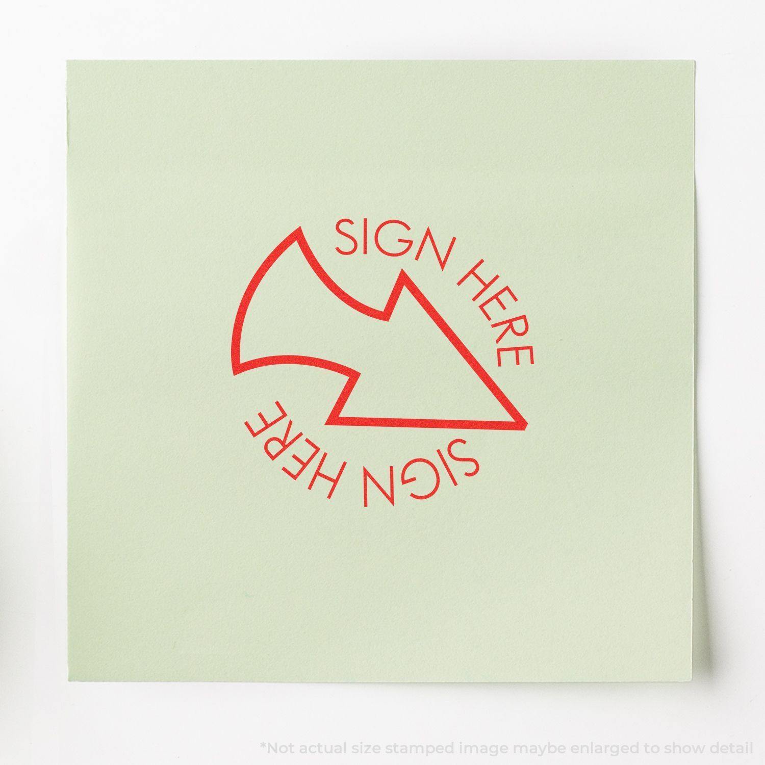 Round Sign Here with Arrow Rubber Stamp in red ink on a light green paper, showing the text SIGN HERE around a curved arrow.