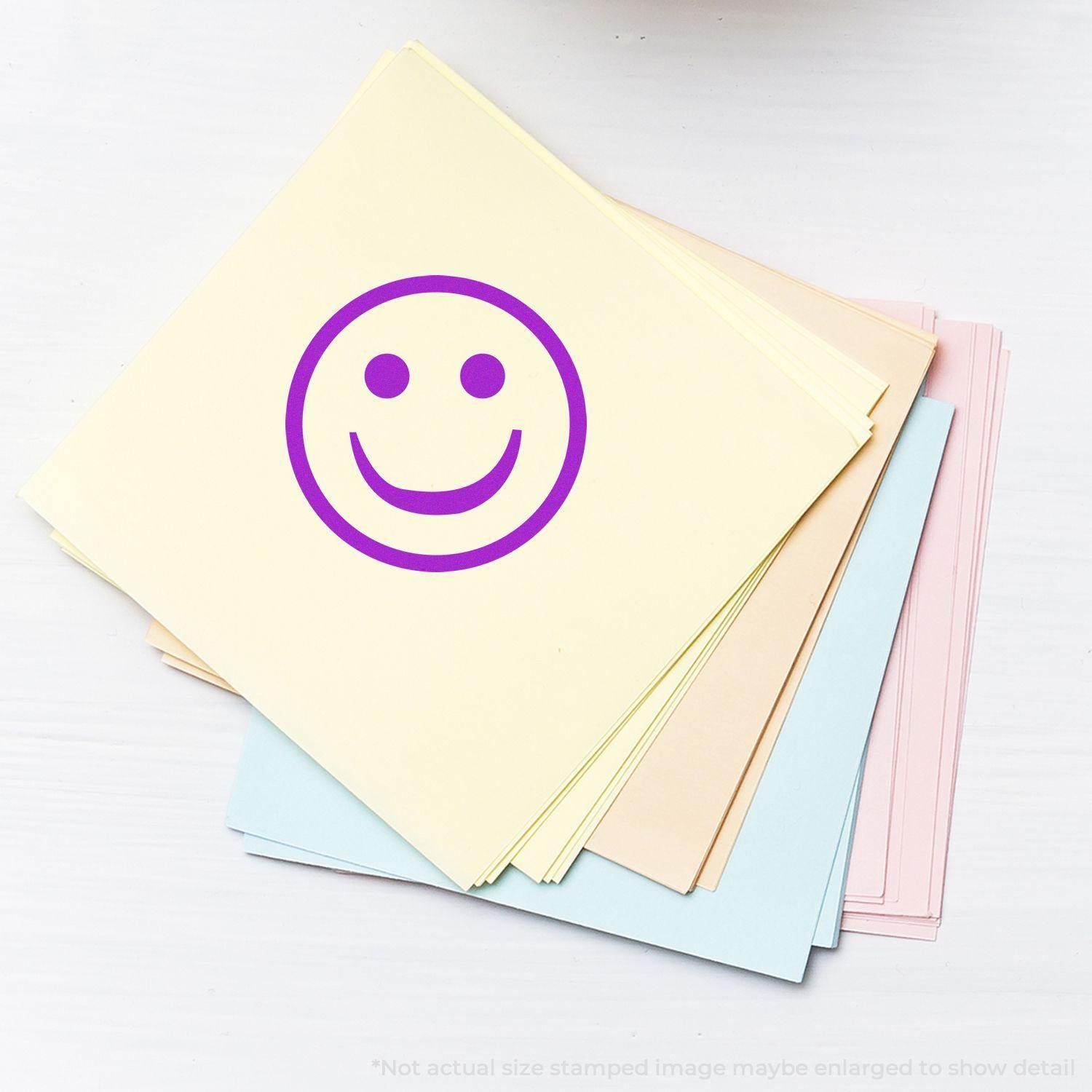 Round Smiley Rubber Stamp in purple ink on a stack of pastel-colored papers, showcasing a cheerful smiley face design.