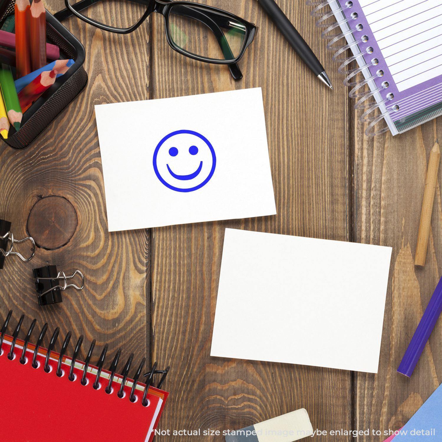 Desk with stationery items, two blank cards, one stamped with a blue round smiley rubber stamp.