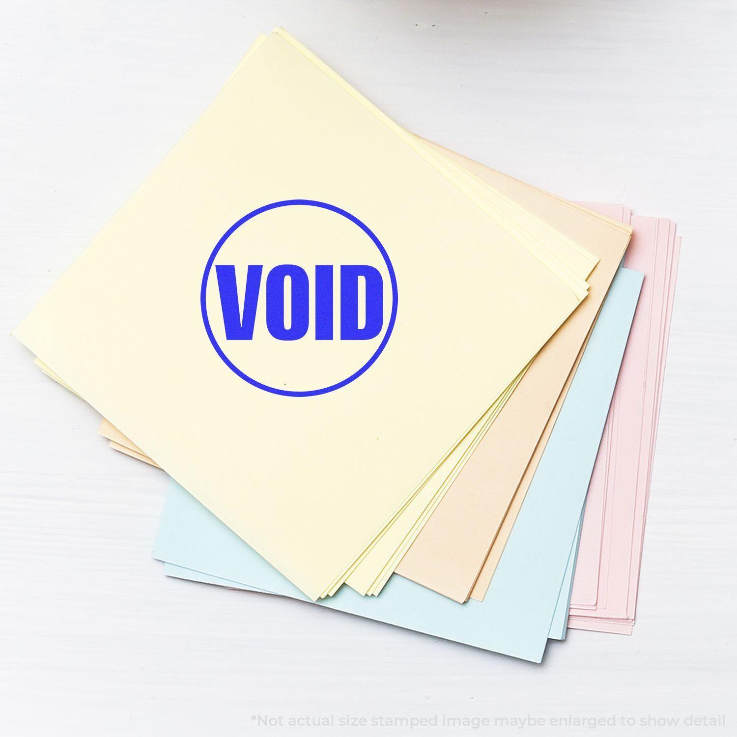 Round Void Rubber Stamp marked in blue ink on a stack of pastel-colored papers, indicating the documents are void.