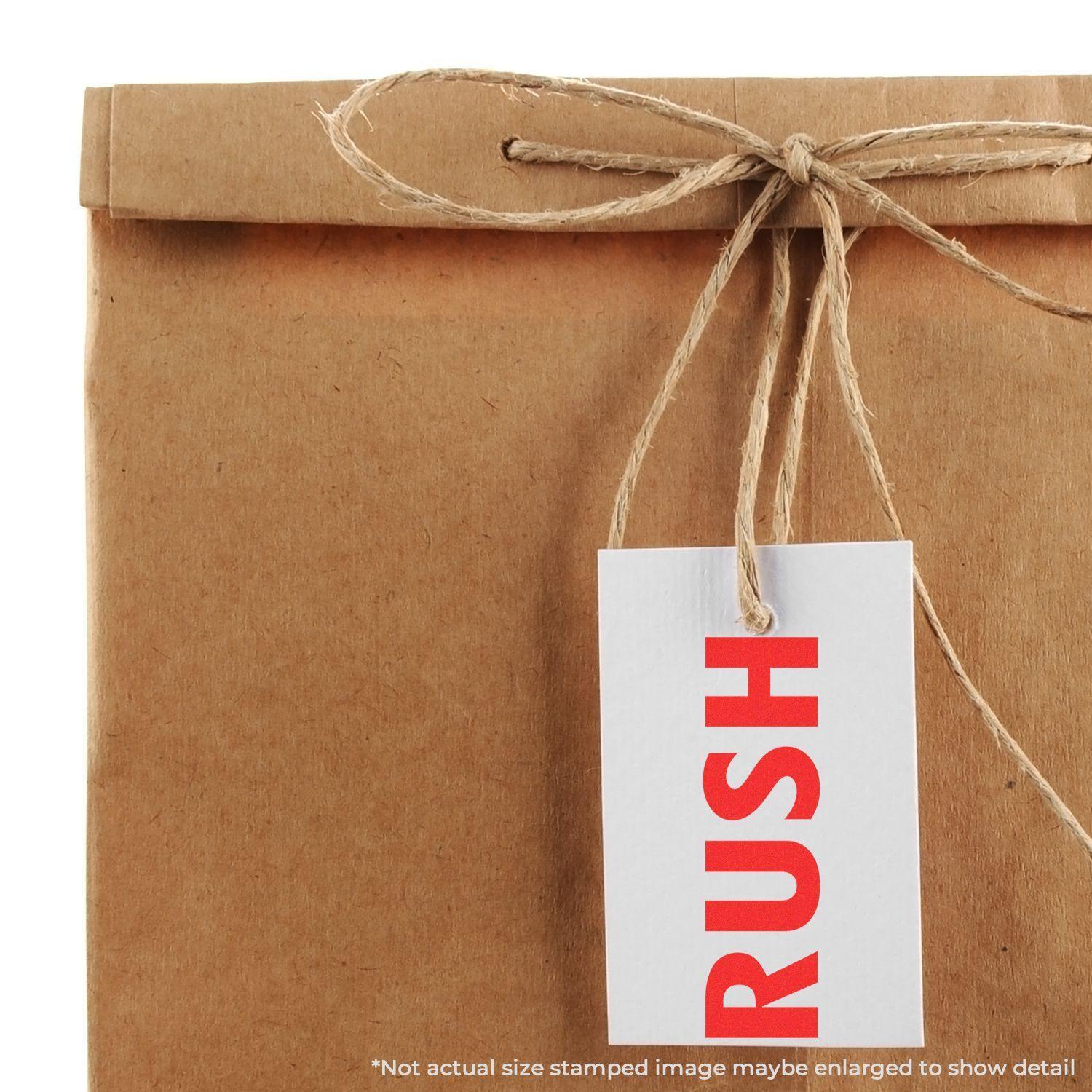 A brown paper package tied with twine and a white tag stamped with RUSH in red using a Slim Pre-Inked Rush Stamp.