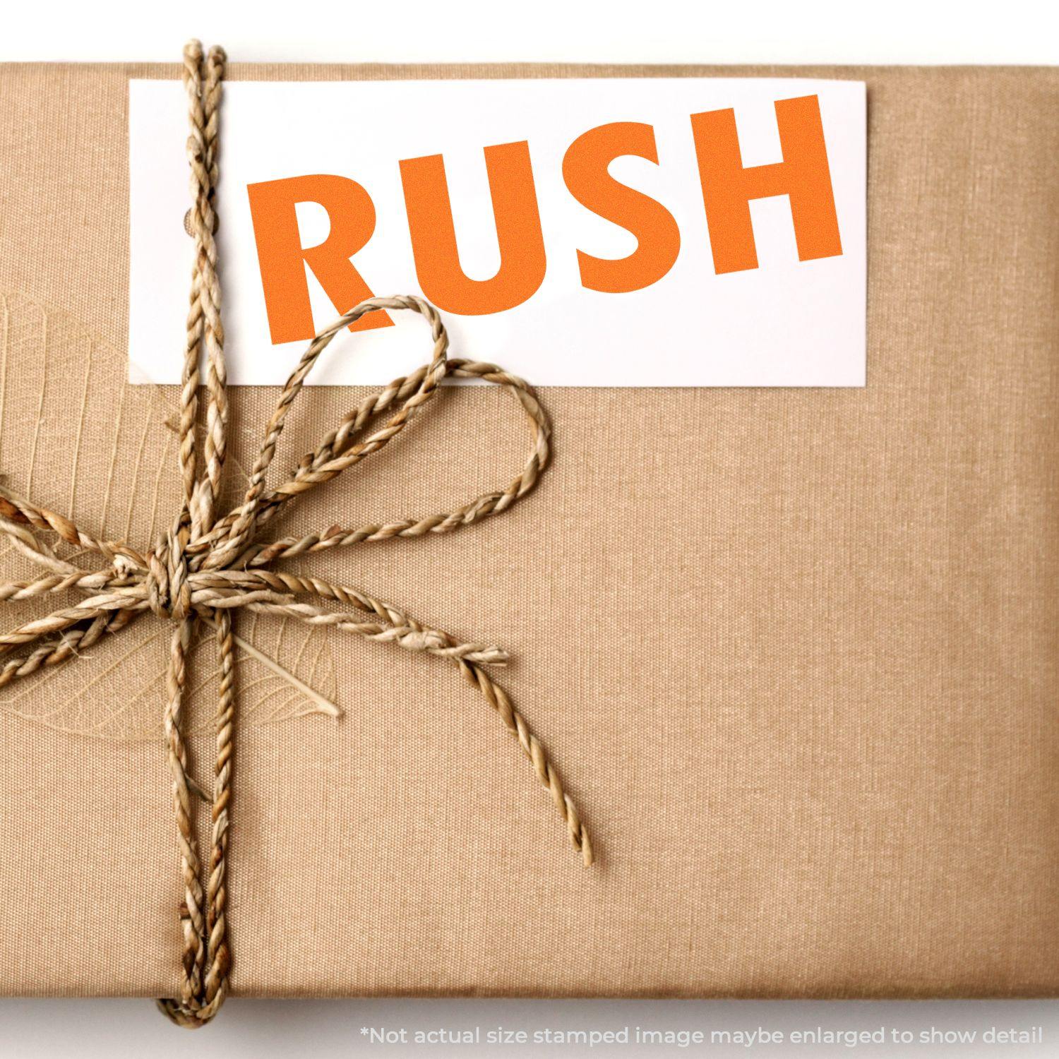 A package wrapped in brown paper with a twine bow, stamped with RUSH using the Large Self Inking Rush Stamp in bold orange letters.