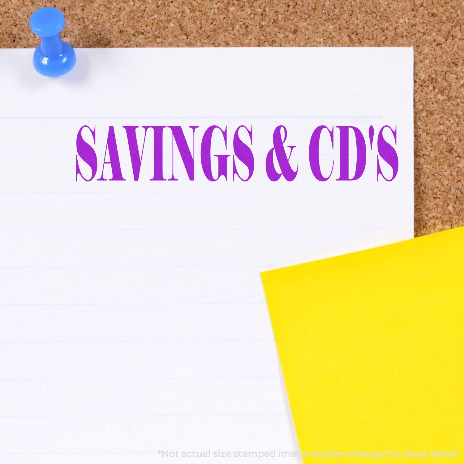 Large Self Inking Savings & CD's Stamp in purple ink on white paper pinned to a corkboard with a blue pushpin and a yellow sticky note.