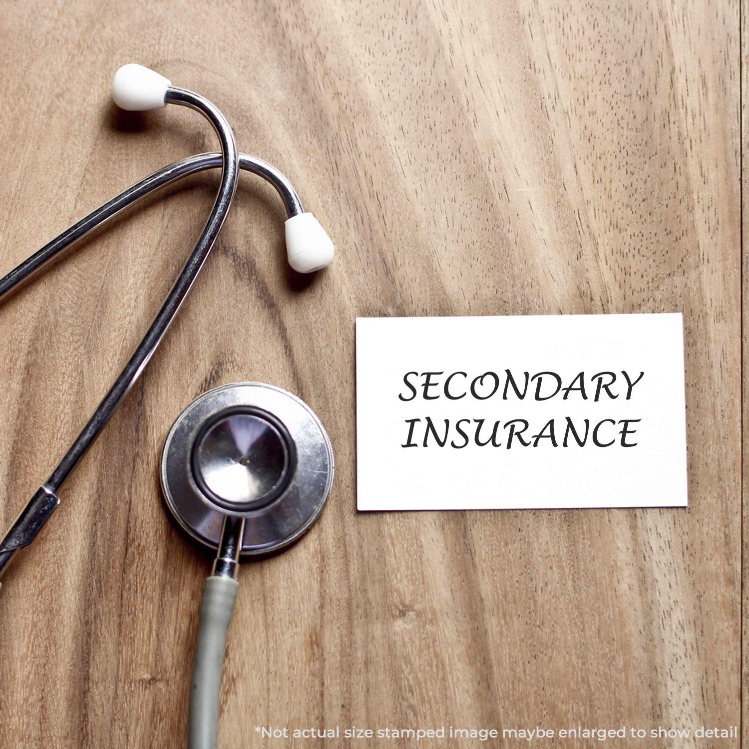 Stethoscope on wooden table next to a card stamped with SECONDARY INSURANCE using a Slim Pre-Inked Secondary Insurance Stamp.