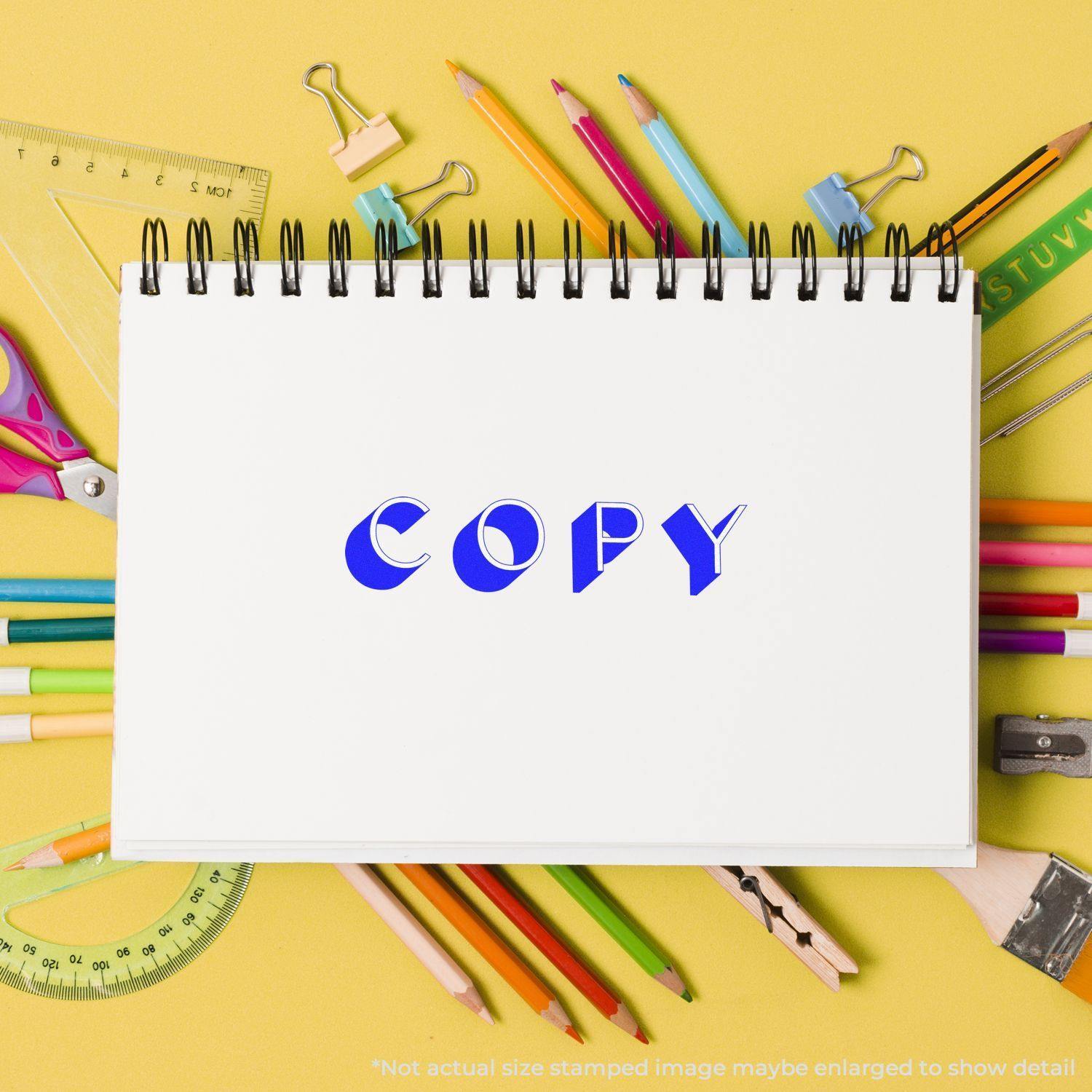 A Large Self Inking Shadow Copy Stamp imprint on a white notebook surrounded by colorful stationery on a yellow background.