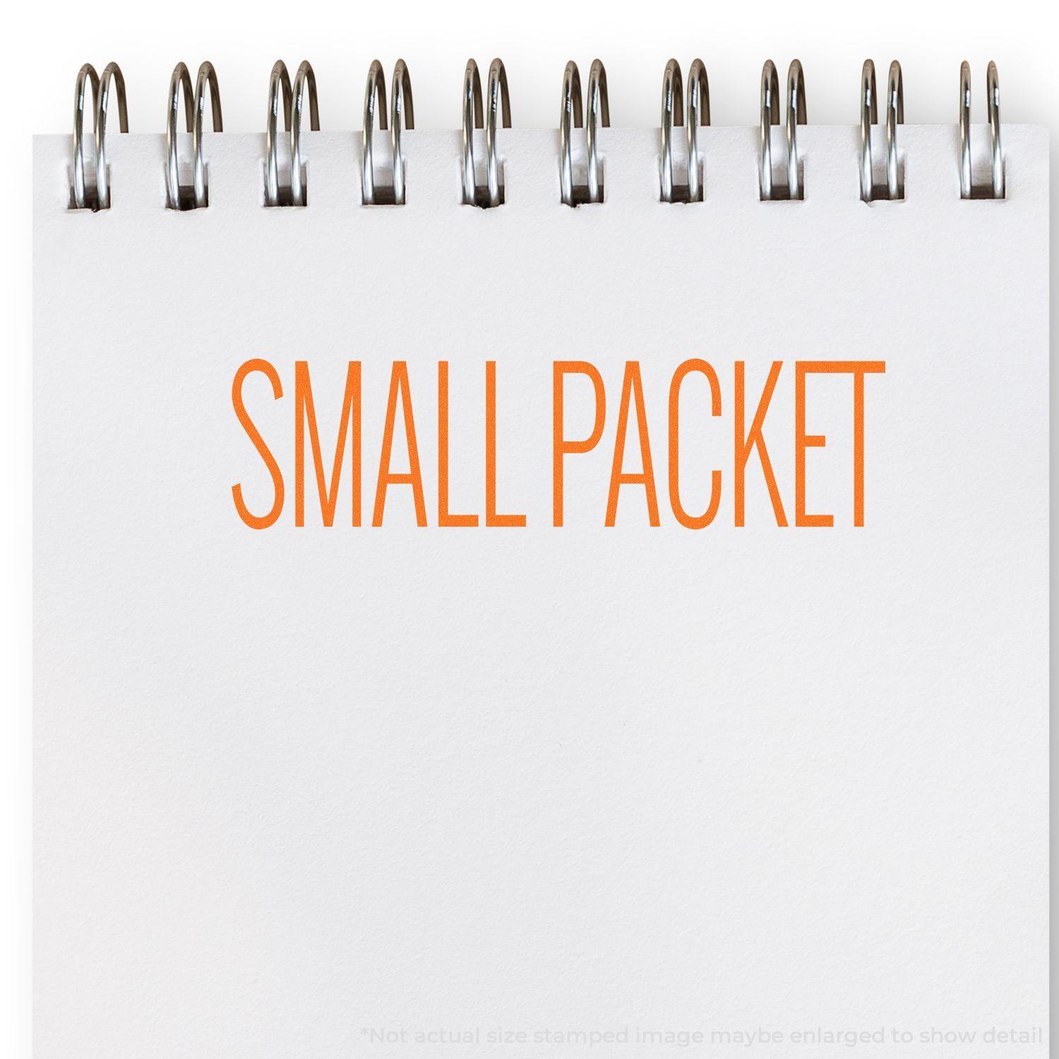 A Large Pre-Inked Small Packet Stamp is used to imprint SMALL PACKET in orange ink on a white notepad with a spiral binding.