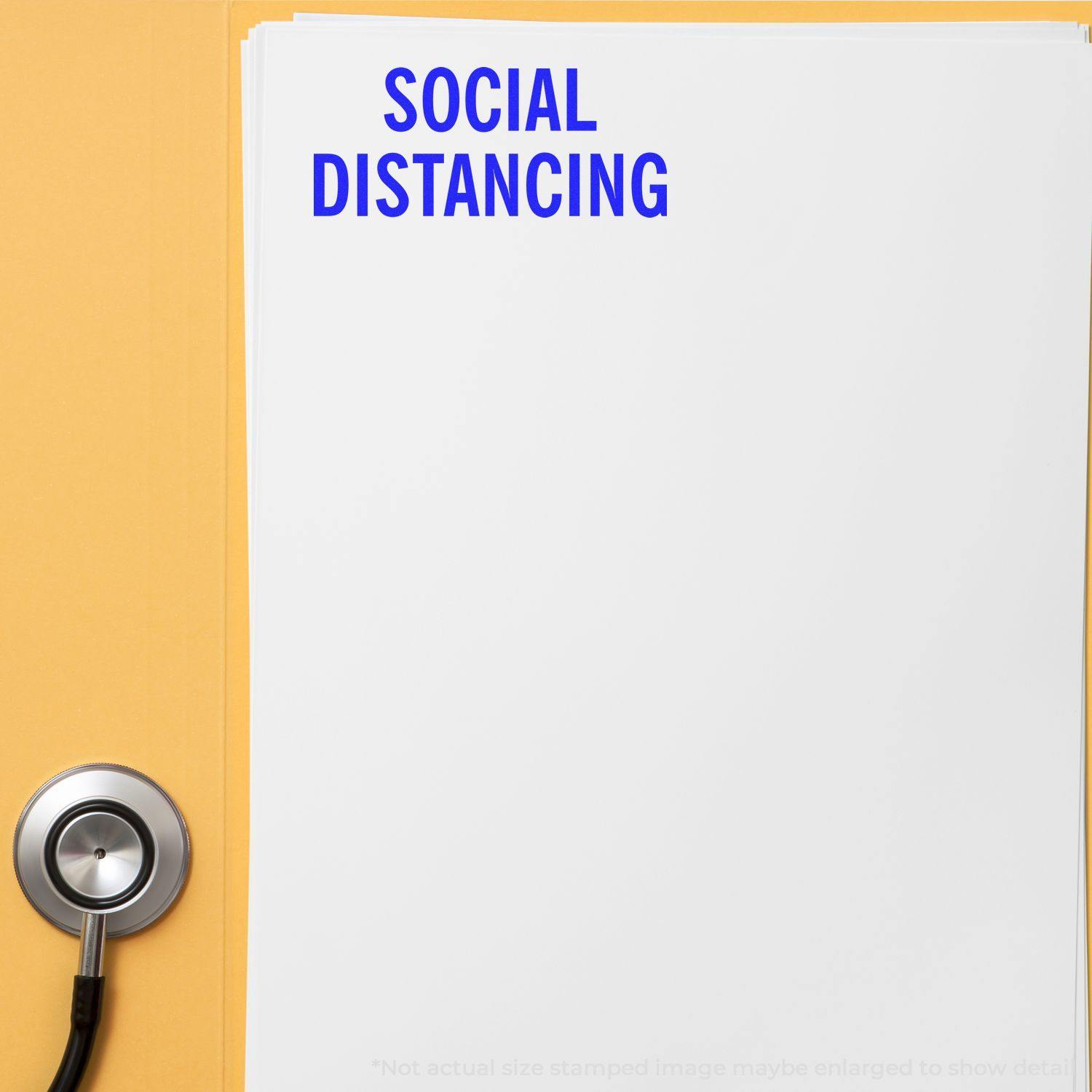 A white paper stamped with SOCIAL DISTANCING in blue ink, using the Self Inking Social Distancing Stamp, next to a stethoscope on a yellow surface.