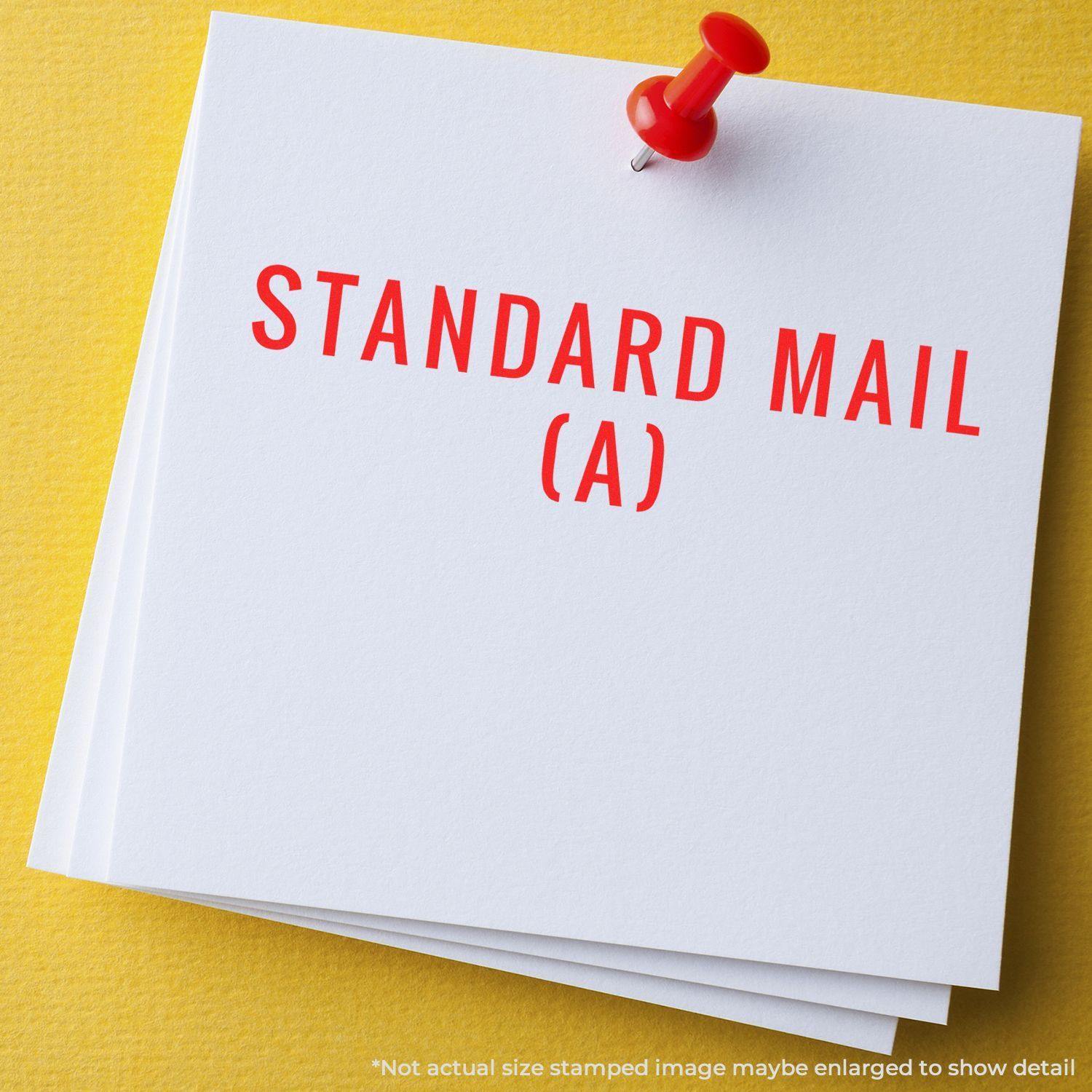 Red Standard Mail (A) rubber stamp impression on white paper pinned with a red pushpin against a yellow background.