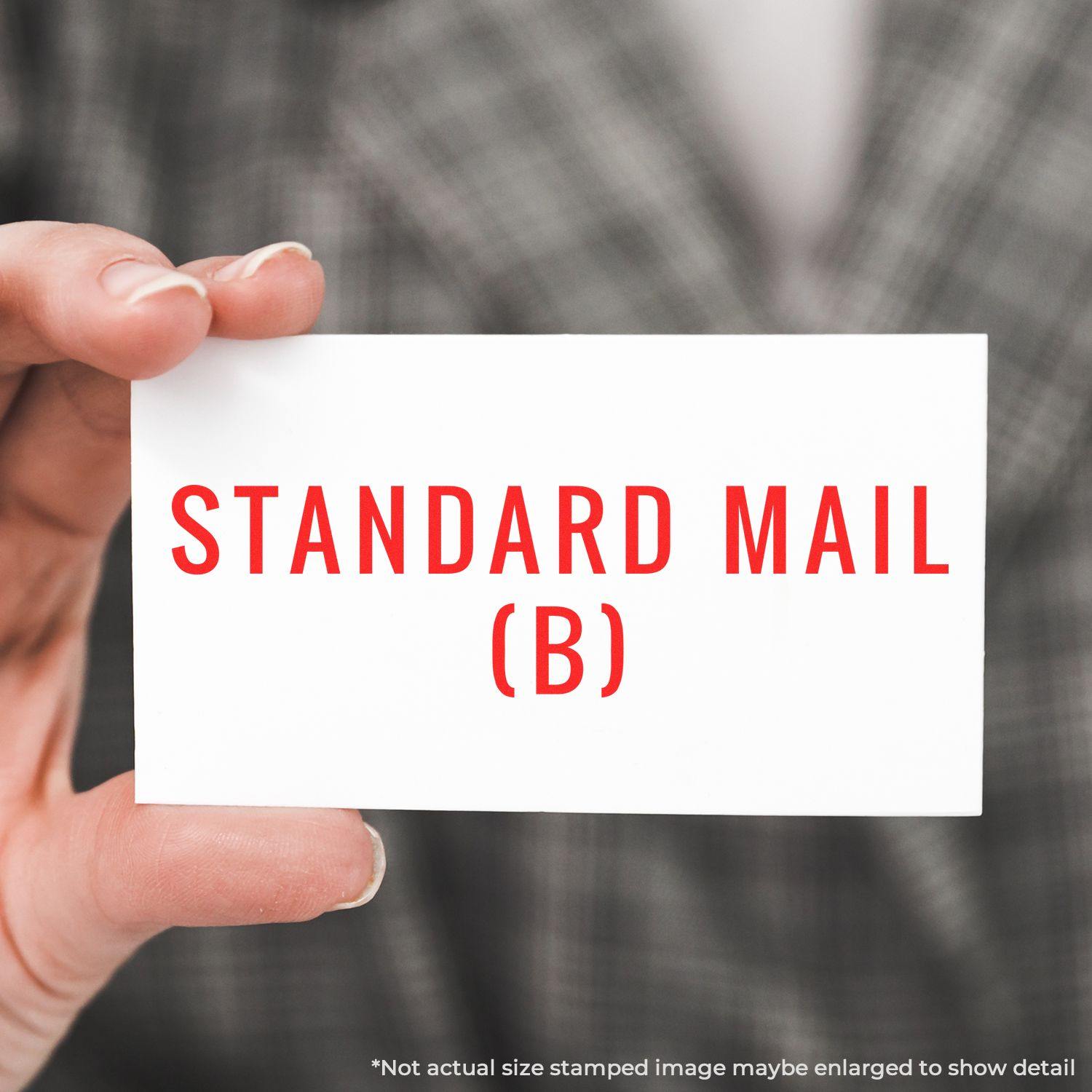 A hand holding a card stamped with STANDARD MAIL (B) in red ink using a Slim Pre-Inked Standard Mail (B) Stamp.