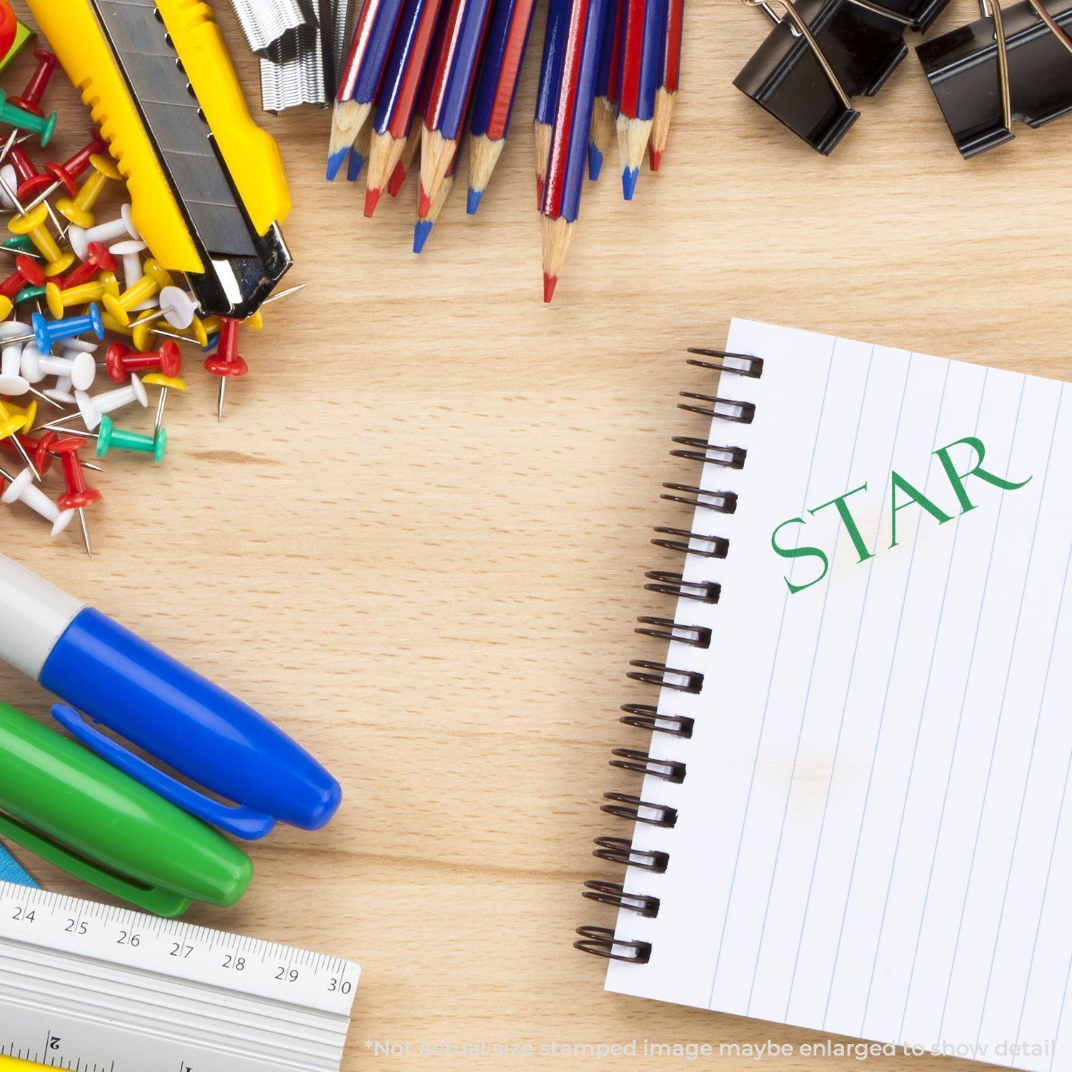 Desk with office supplies, a notebook stamped with STAR using the Large Pre-Inked Star Stamp, surrounded by pens, push pins, and clips.