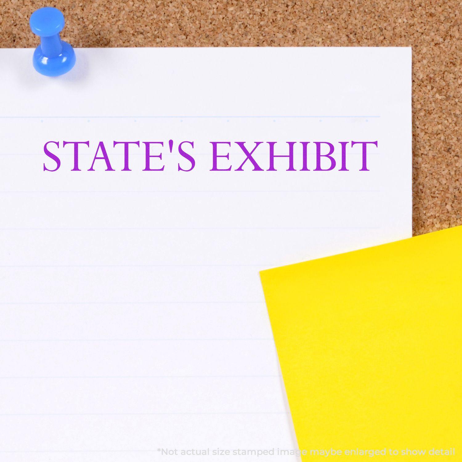 Large Pre-Inked States Exhibit Stamp used on white paper pinned to a corkboard, with STATE'S EXHIBIT stamped in purple ink.