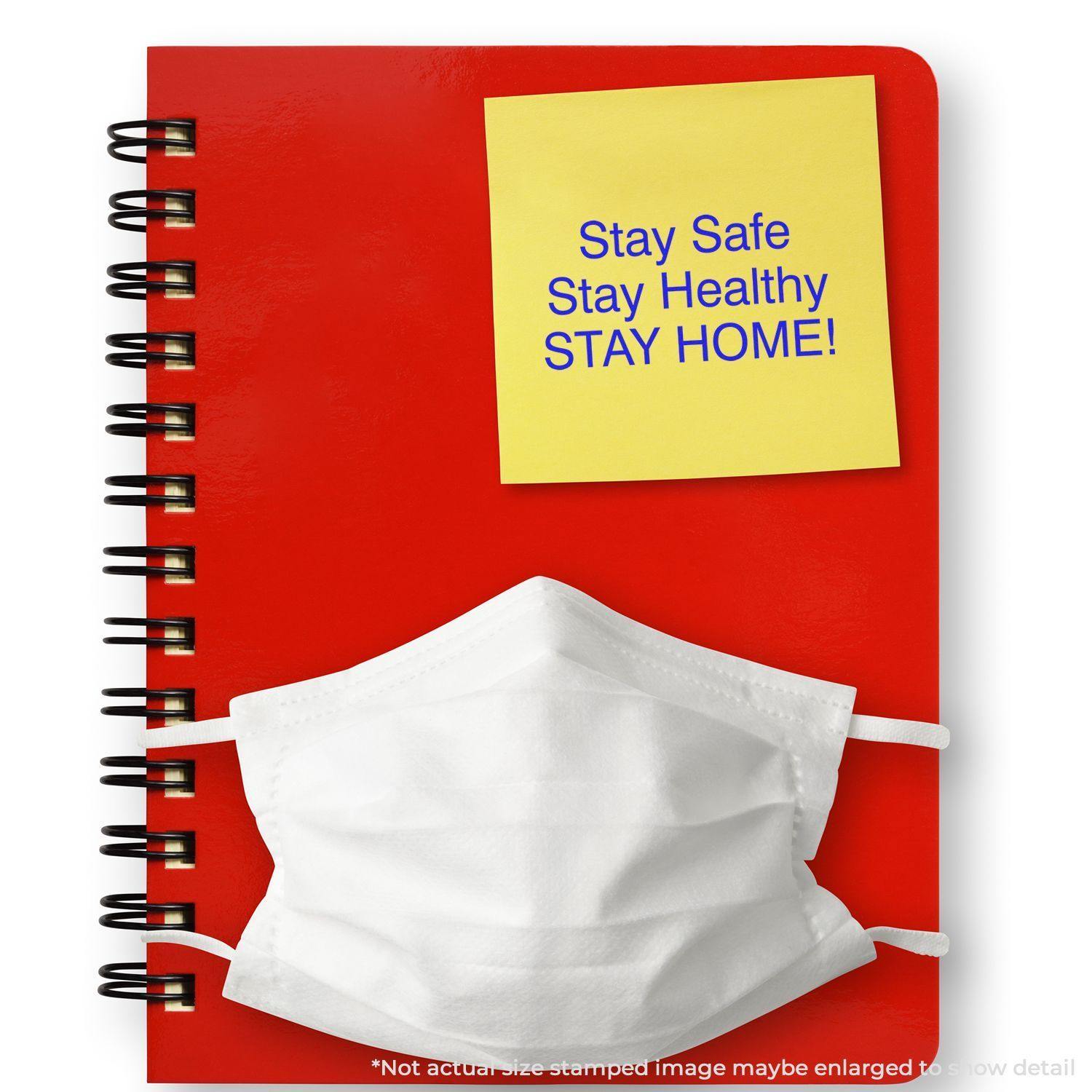 Red notebook with a yellow sticky note stamped Stay Safe Stay Healthy Stay Home! and a white face mask placed on top.