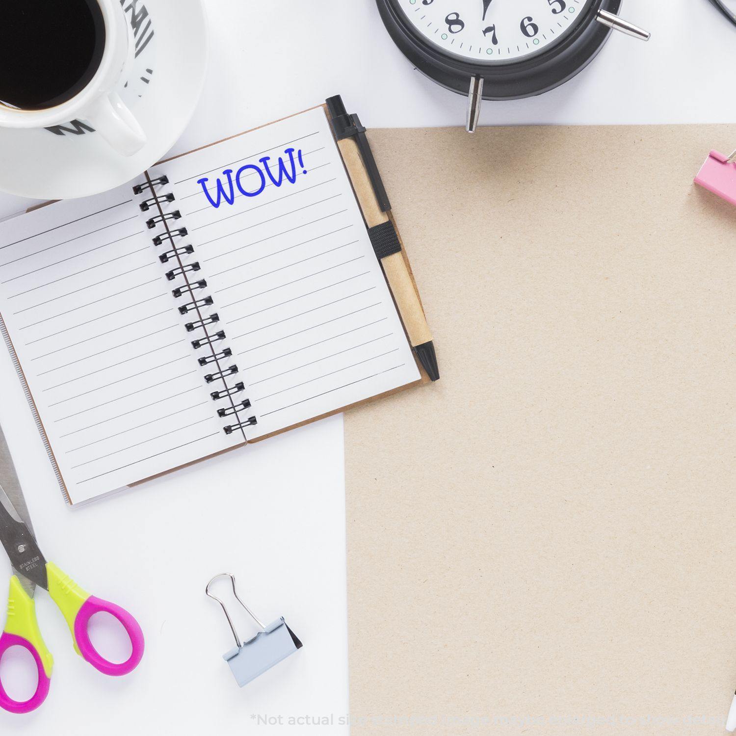 Open notebook stamped with WOW! using a Slim Pre-Inked WOW Stamp, surrounded by office supplies and a clock.