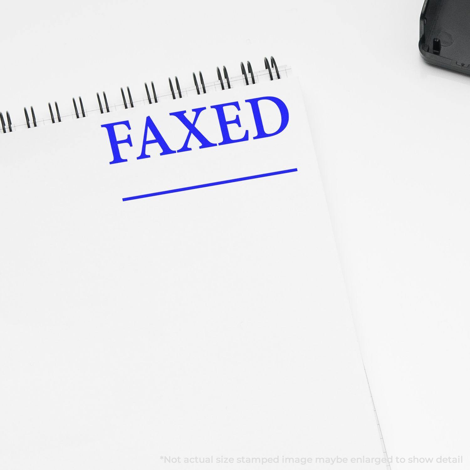 Large Pre-Inked Times Faxed with Line Stamp in blue ink on a white notepad, showing the word FAXED and a line below it.