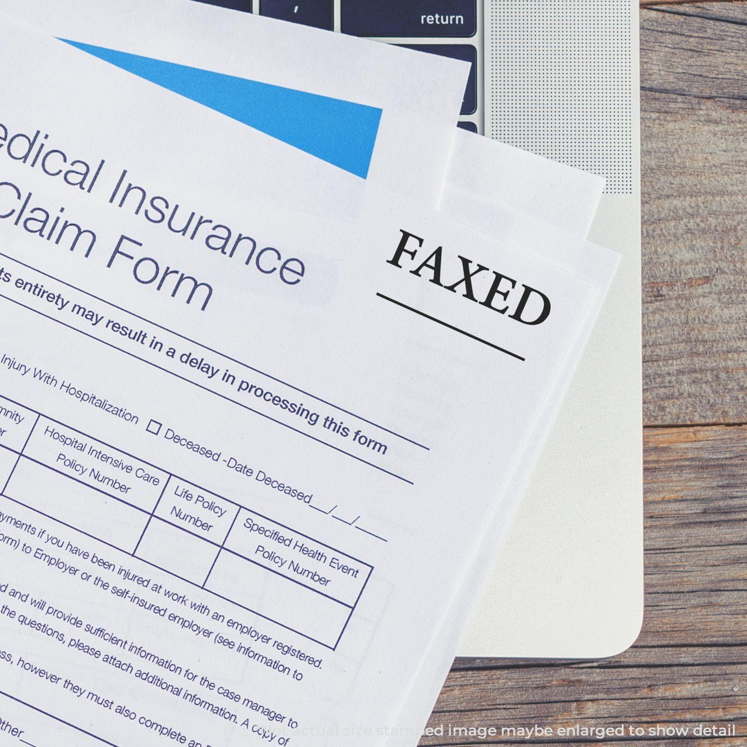 Medical insurance claim form stamped with FAXED using the Large Pre-Inked Times Faxed with Line Stamp, placed on a laptop keyboard.