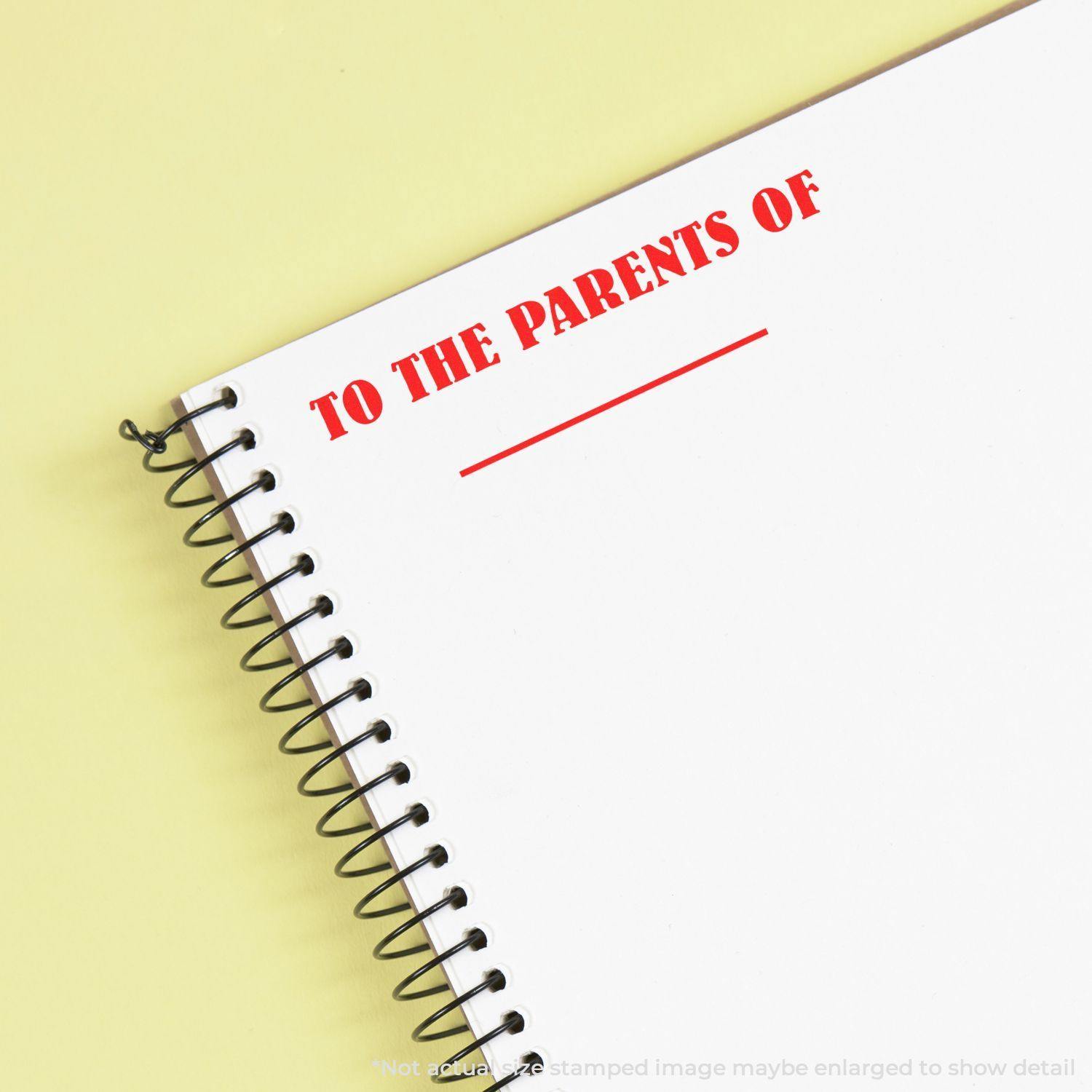 Large Self Inking To The Parents Of Stamp in red ink on a white spiral notebook, with yellow background.