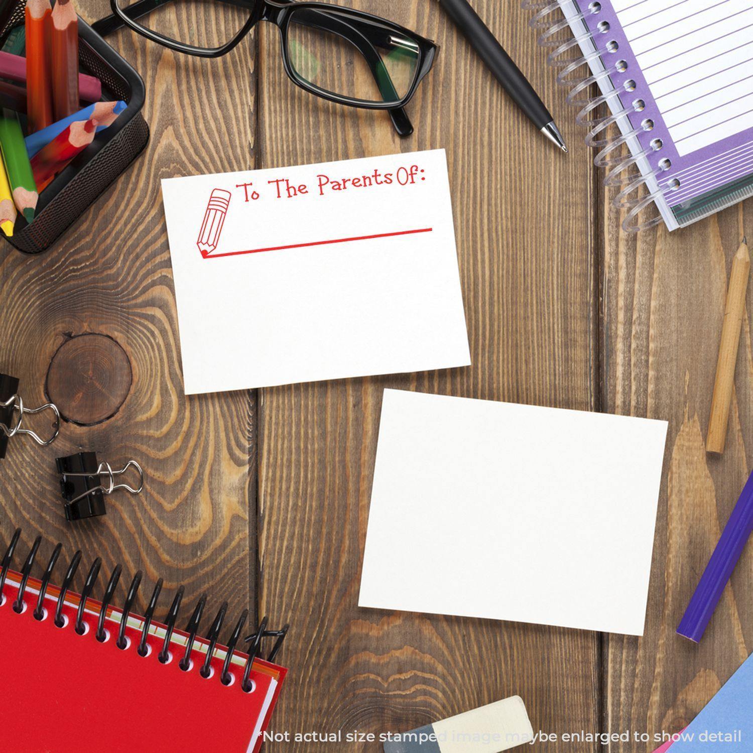 Large Self Inking To The Parents Of with Line Stamp on a wooden desk with stationery, glasses, and notebooks.