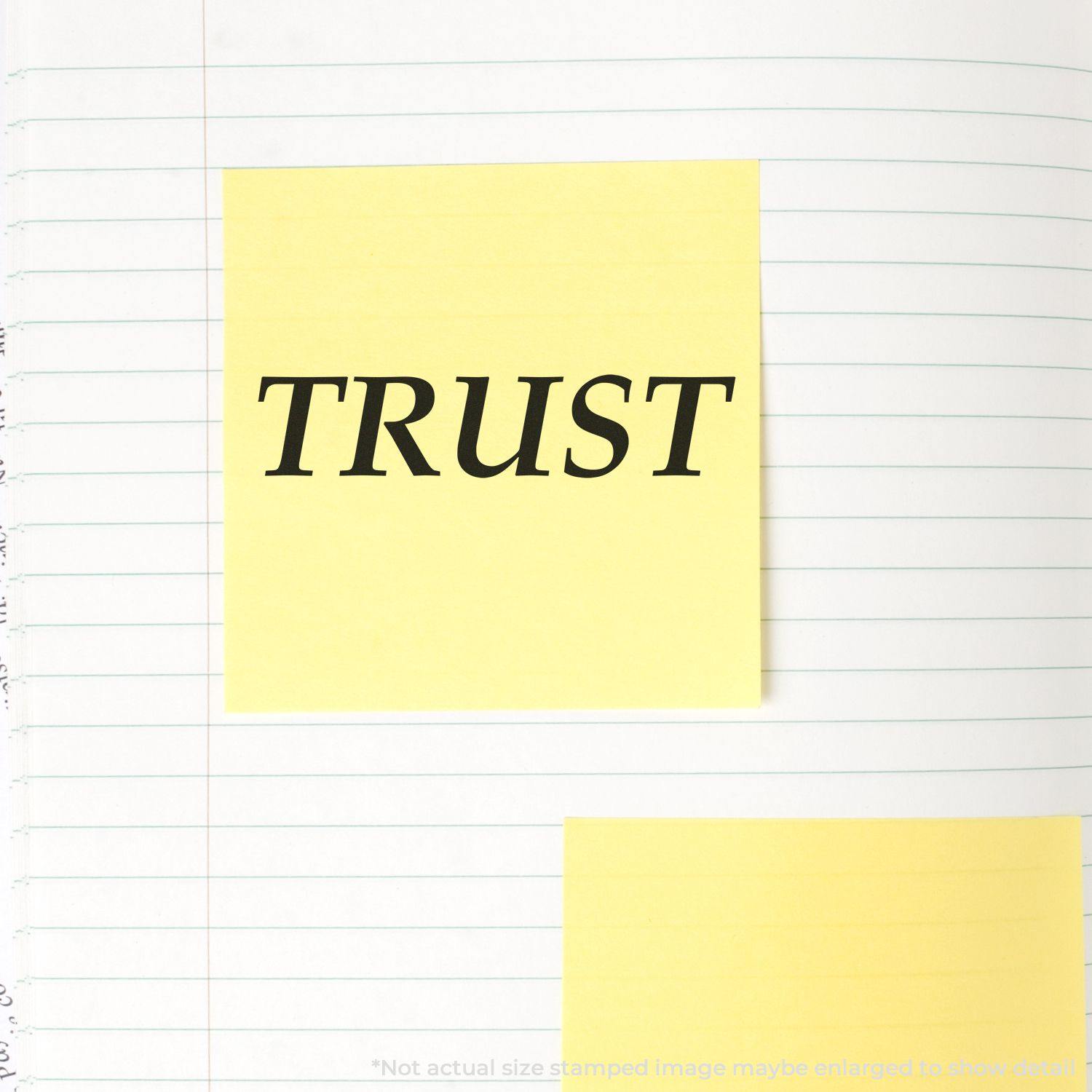 Yellow sticky note with the word TRUST stamped on it using the Large Pre-Inked Trust Stamp, placed on a lined notebook page.