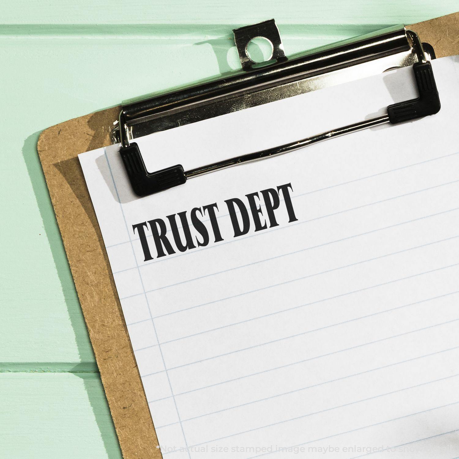 Slim Pre-Inked Trust Dept Stamp used on a clipboard with lined paper, displaying the text TRUST DEPT in bold letters.