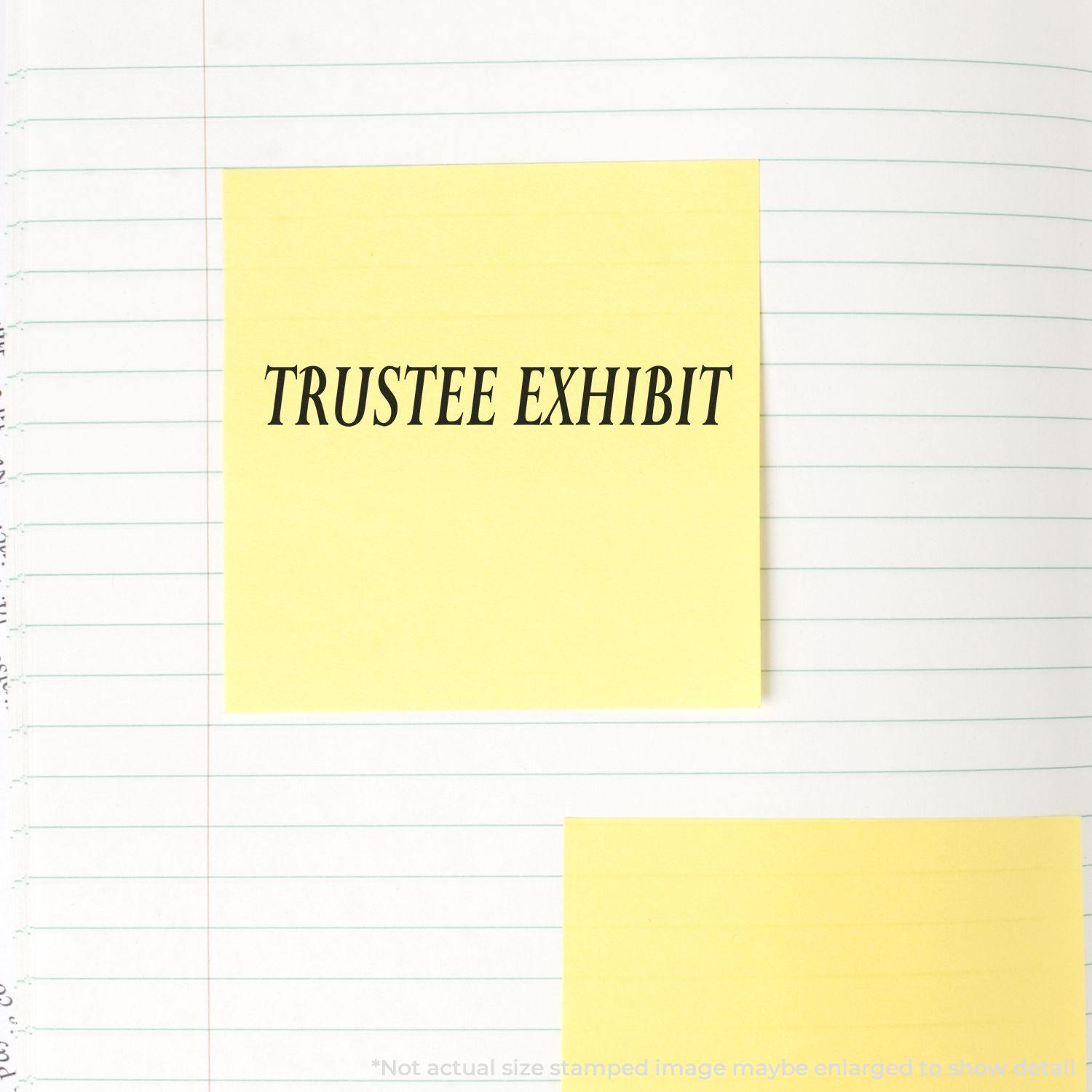 Slim Pre-Inked Trustee Exhibit Stamp used on a yellow sticky note placed on a lined notebook page.