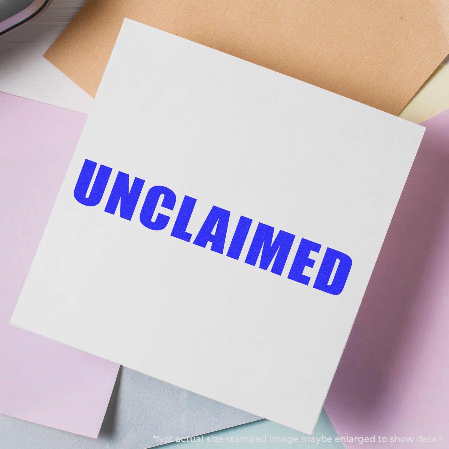 Self Inking Unclaimed Stamp in blue ink on a white paper, surrounded by pastel-colored papers on a desk.