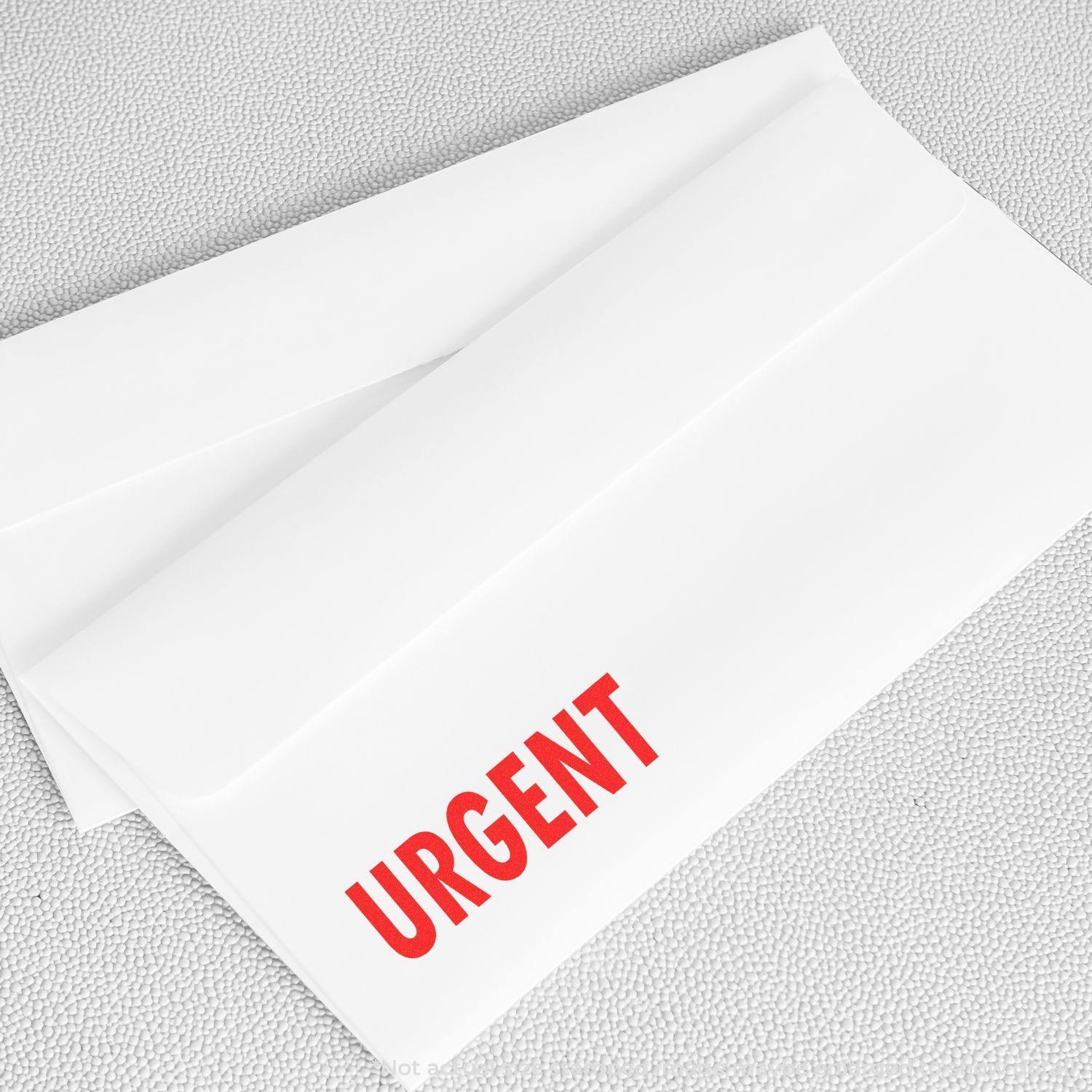 White envelope stamped with URGENT in red using the Self Inking Urgent Stamp, placed on a light gray textured surface.