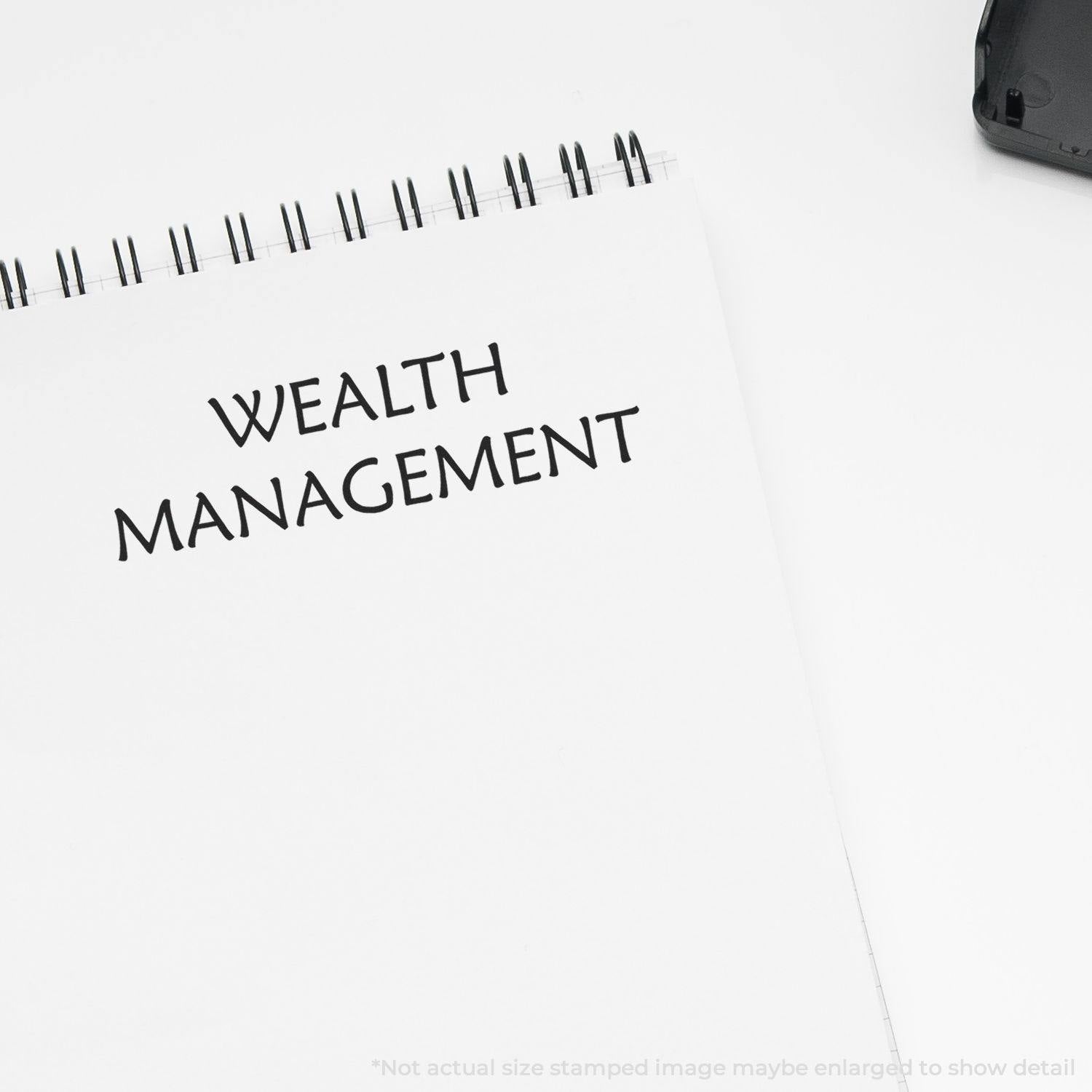 Large Wealth Management rubber stamp imprint on a white notepad with a black ink pad in the corner.