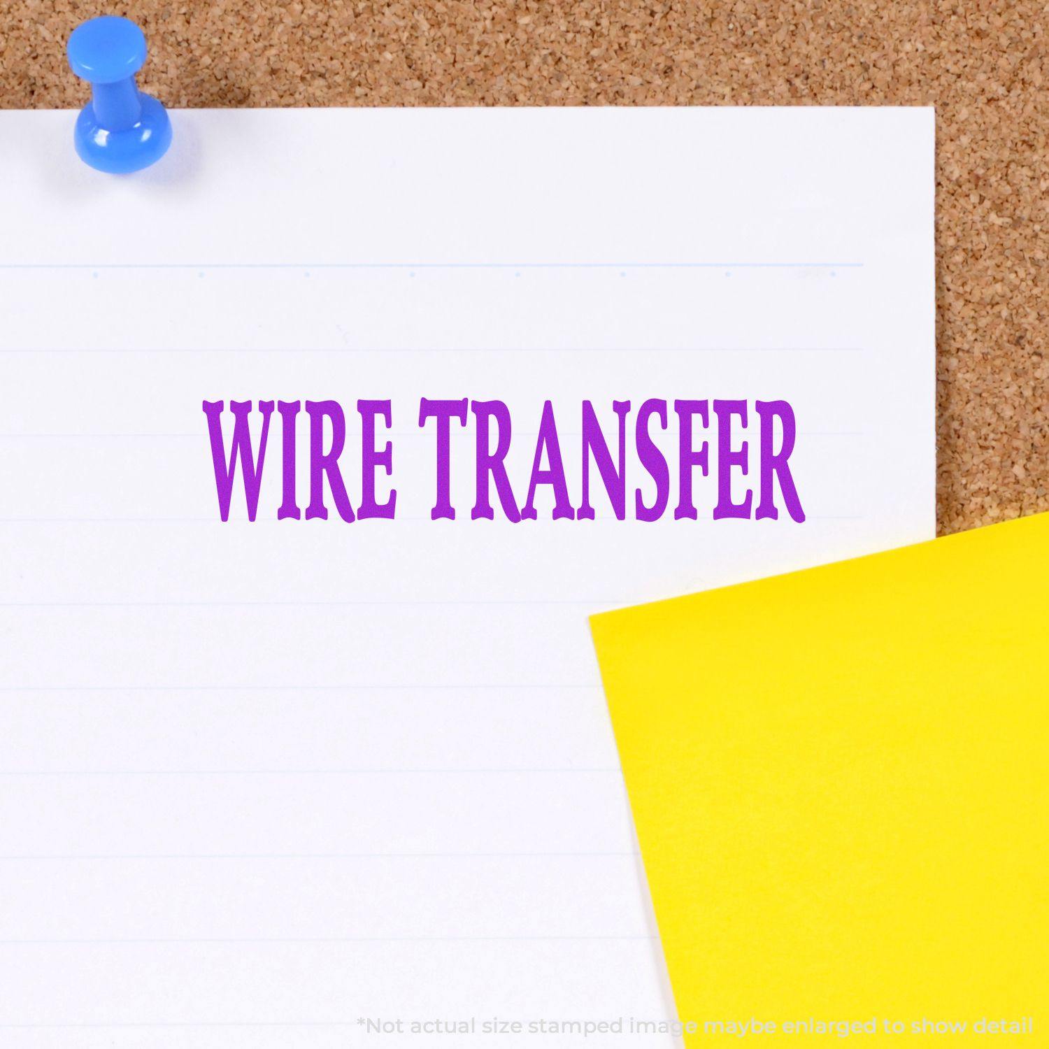 Large Wire Transfer Rubber Stamp in purple ink on white paper pinned to a corkboard with a yellow note beside it.