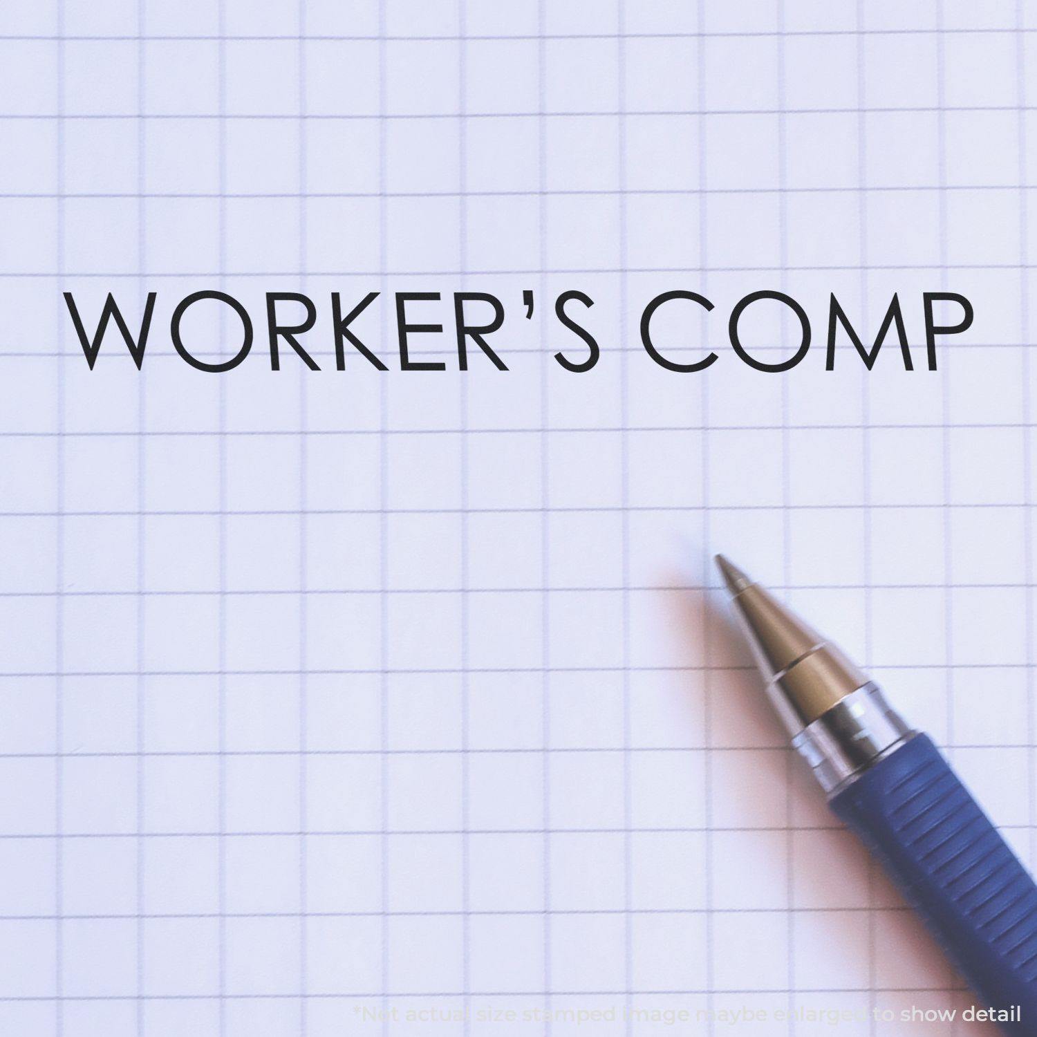 A blue pen next to a WORKER'S COMP imprint on grid paper, made using the Large Self Inking Worker's Comp Stamp.