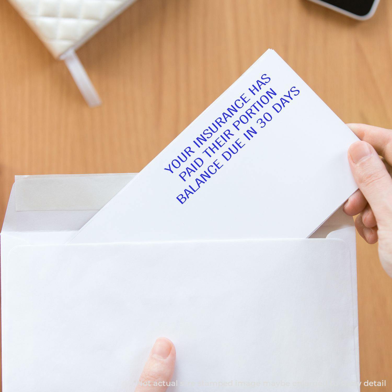 Person holding an envelope with a letter stamped Your Insurance Has Paid Their Portion using a Slim Pre-Inked stamp.